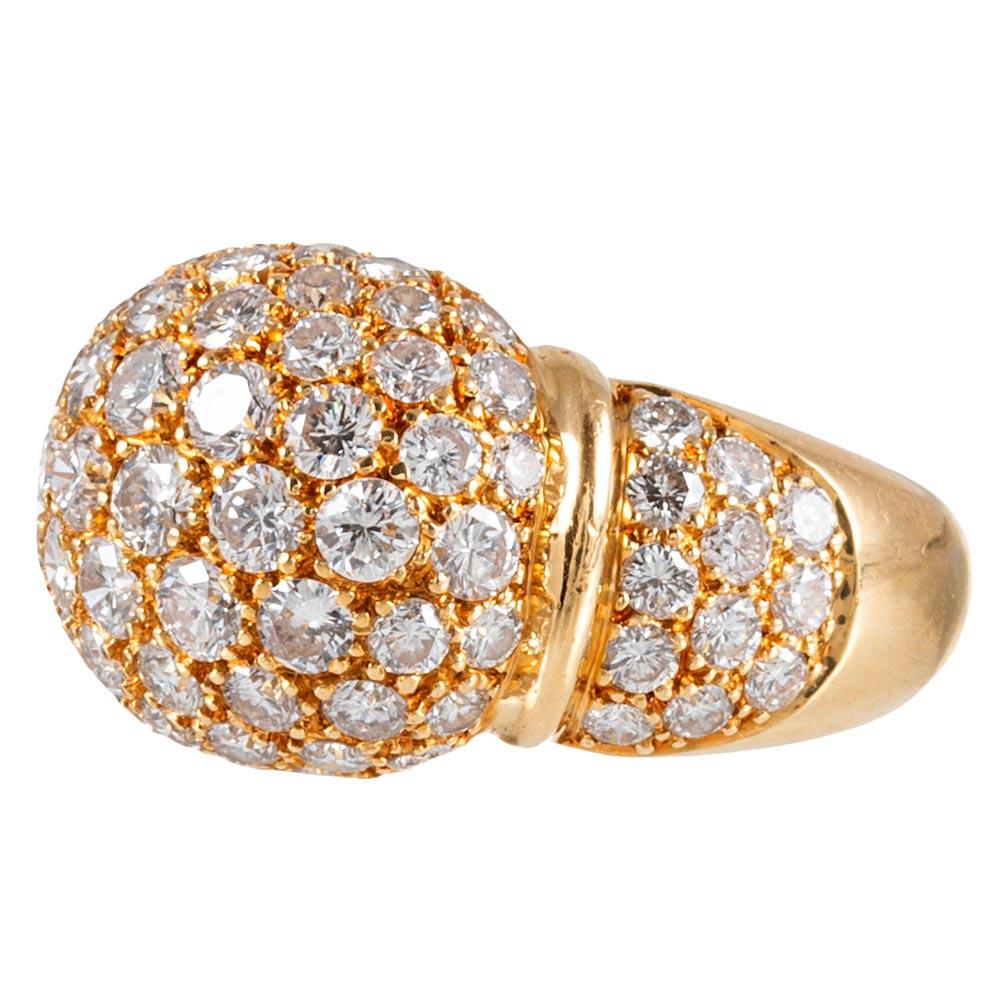 A substantial and sophisticated creation, compliments of Cartier, the ring is rendered in 18 karat yellow gold and set with approximately 3 carats of brilliant white diamonds. The modified dome shape rises gently from the finger without boasting too