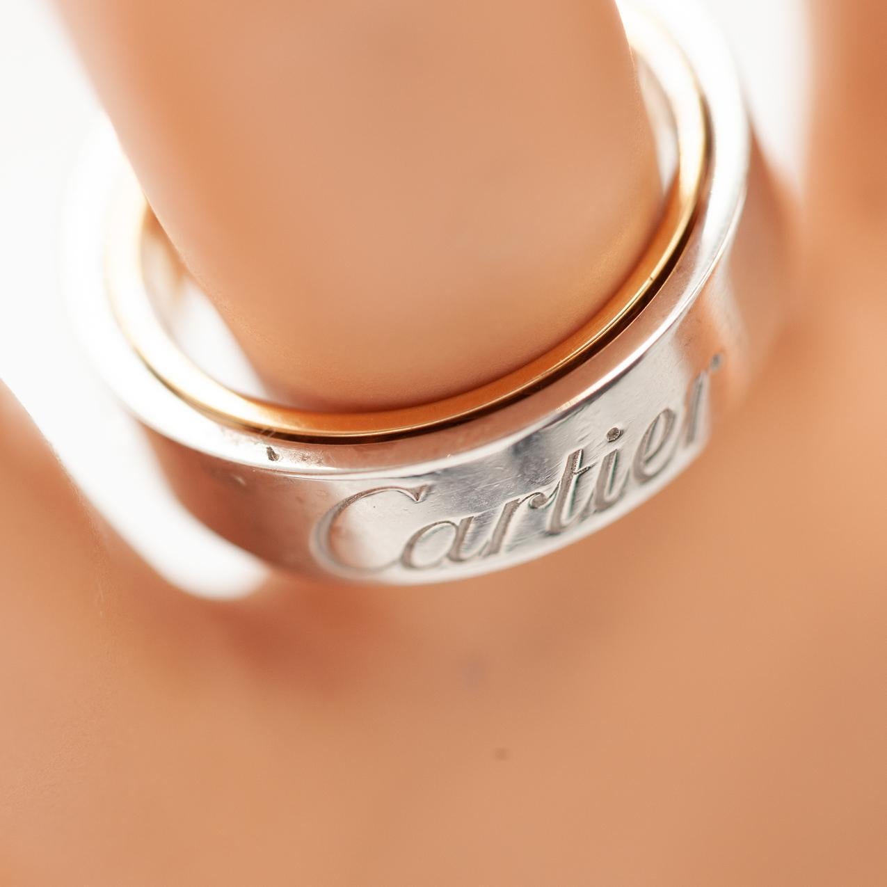 Un raro e da collezione anello Cartier Secret Love, realizzato in una straordinaria combinazione di oro bianco e rosa a 18 carati. Questo ingegnoso design è caratterizzato da due bande rotanti interconnesse. La costruzione innovativa permette a
