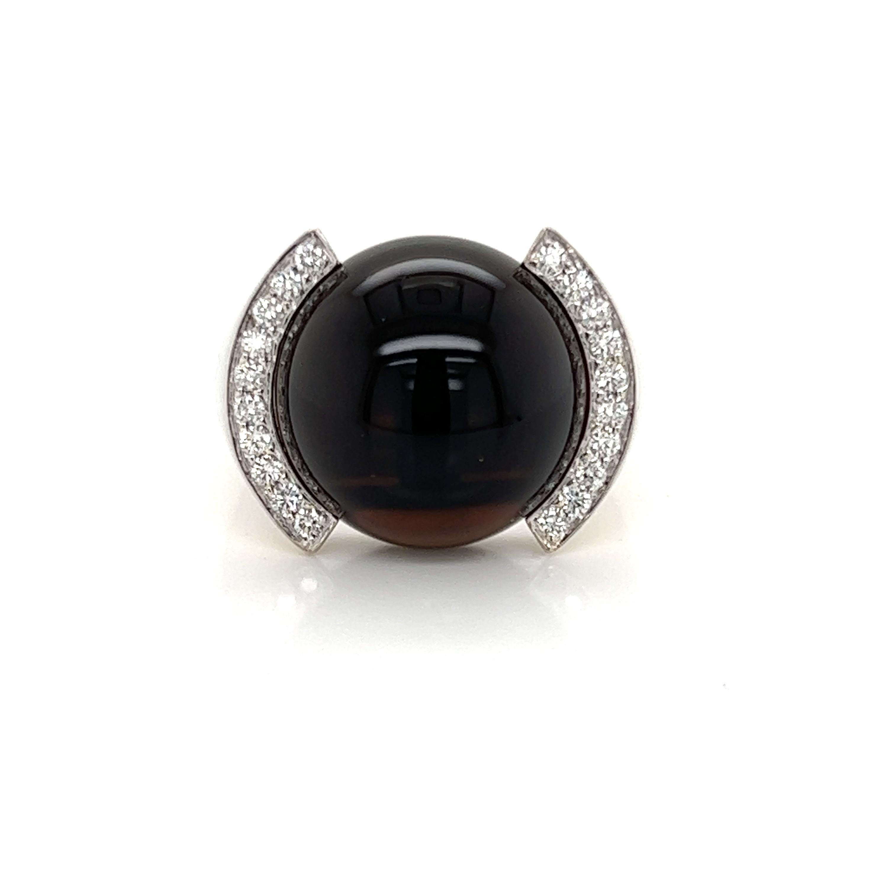 This is a beautiful authentic ring from Cartier. It is crafted from 18k white gold with a polished finish featuring a half bezel set large 16mm round smoky quartz gemstone accented 10 round cut diamond on each side bezel frame. The cabochon dome