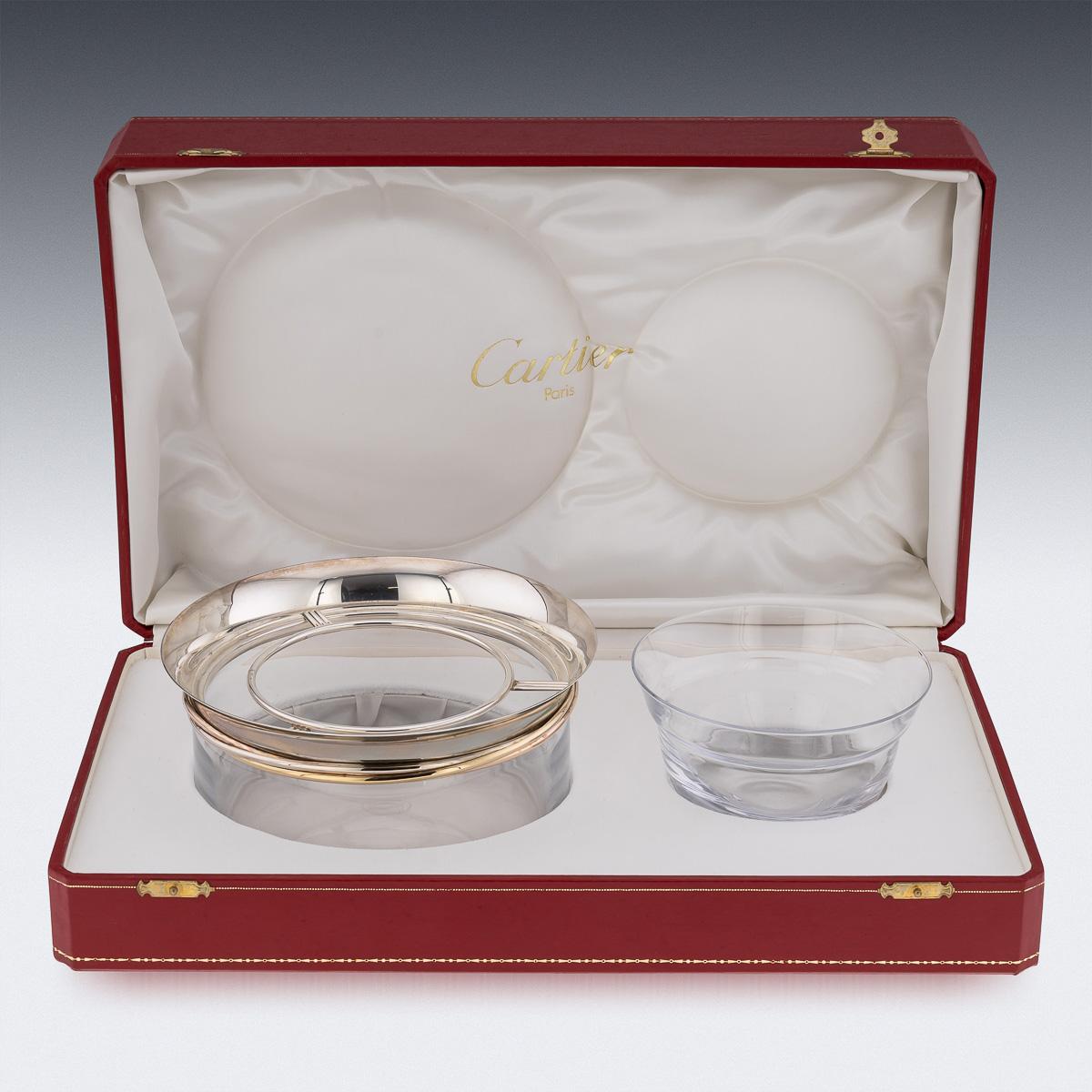 A spectacular Cartier glass caviar bowl and serving spoon, the bowls rim decorated with tri-color gold band and silver border, signed Cartier Paris, inventory numbered. Maker’s mark and assay mark for silver, made in France, and a serving caviar