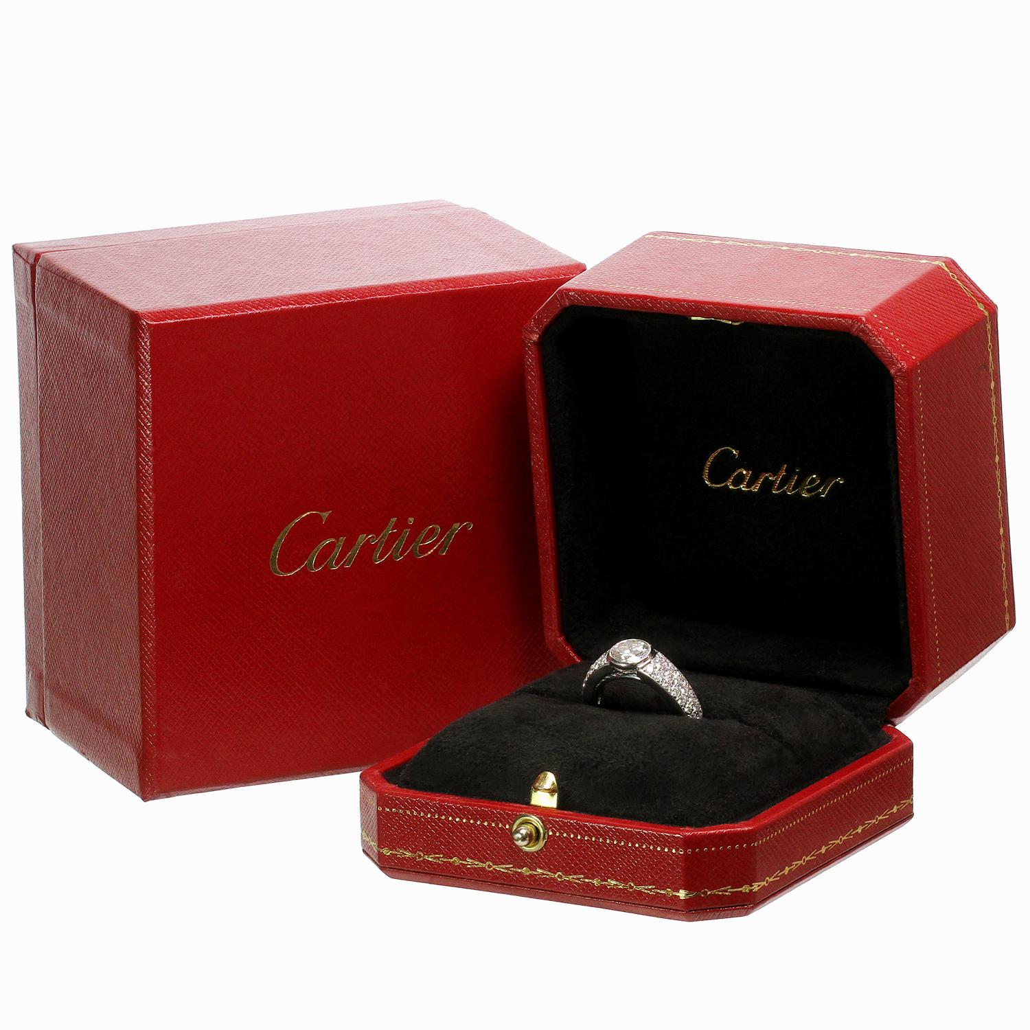 This exquisite Cartier ring is crafted in 18k white gold and features a solitaire 1.01 carat brilliant-cut round diamond in a bezel-setting surrounded with 42 pave-set brilliant-cut round diamonds weighing an estimated 0.52 carats.  Completed with