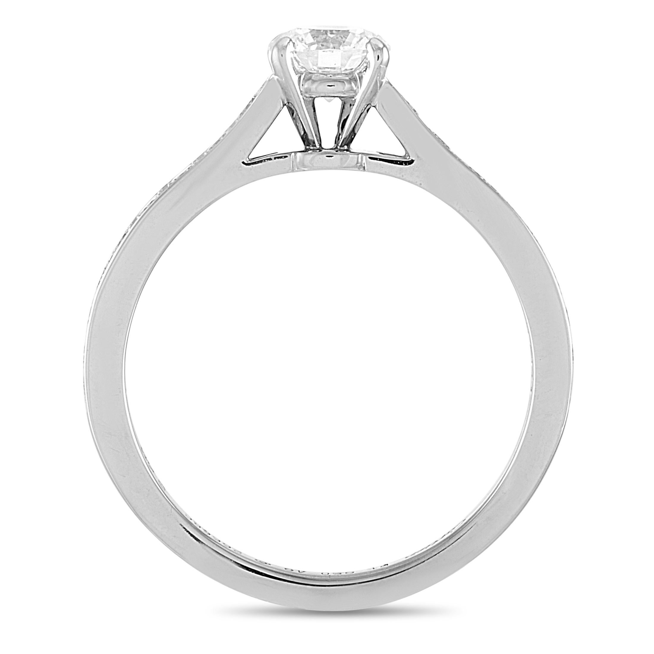 The Cartier “Solitaire” engagement ring is crafted from platinum and weighs 3.2 grams. It boasts band thickness of 2 mm and top height of 6 mm, while top dimensions measure 5 by 18 mm. The ring is set with a total of 0.60 carats of diamonds – the