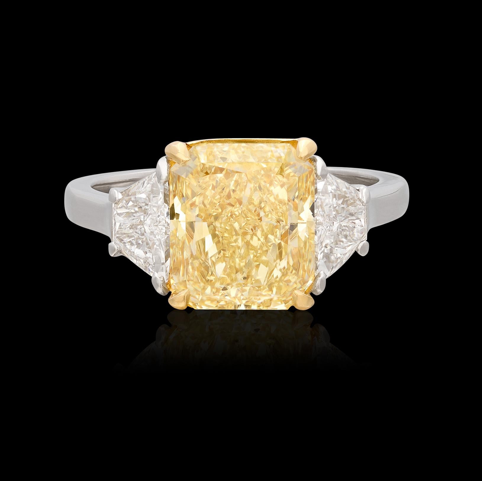 A genuine showstopper! Show your true colors with this extraordinary Cartier stamped diamond ring featuring a 4.30 carat GIA Fancy Yellow Radiant Cut Natural Diamond flanked on either side by phenomenal Trapezoid Cut Diamonds weighing together 1.50