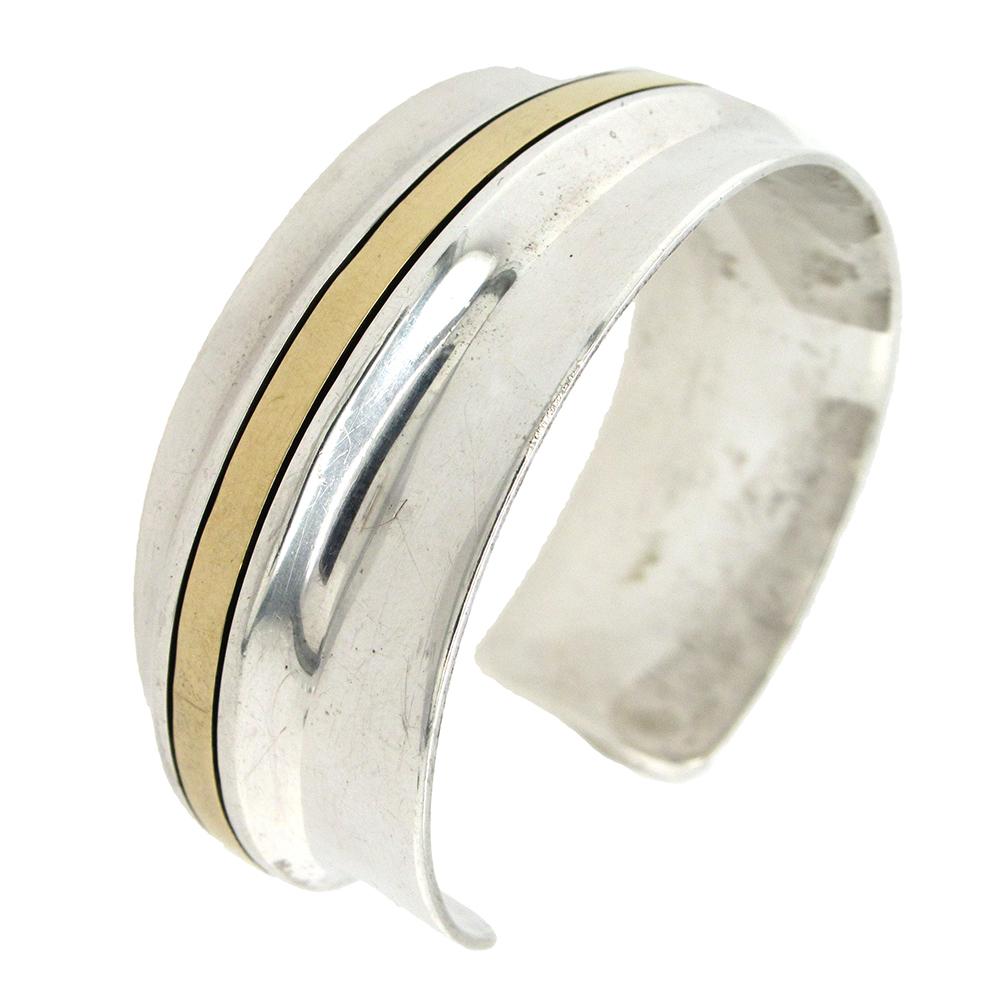 Two-tone cuff bracelet in sterling silver and  inlaid curved stripe of 18K yellow gold by Cartier circa 1970's measures 3/4