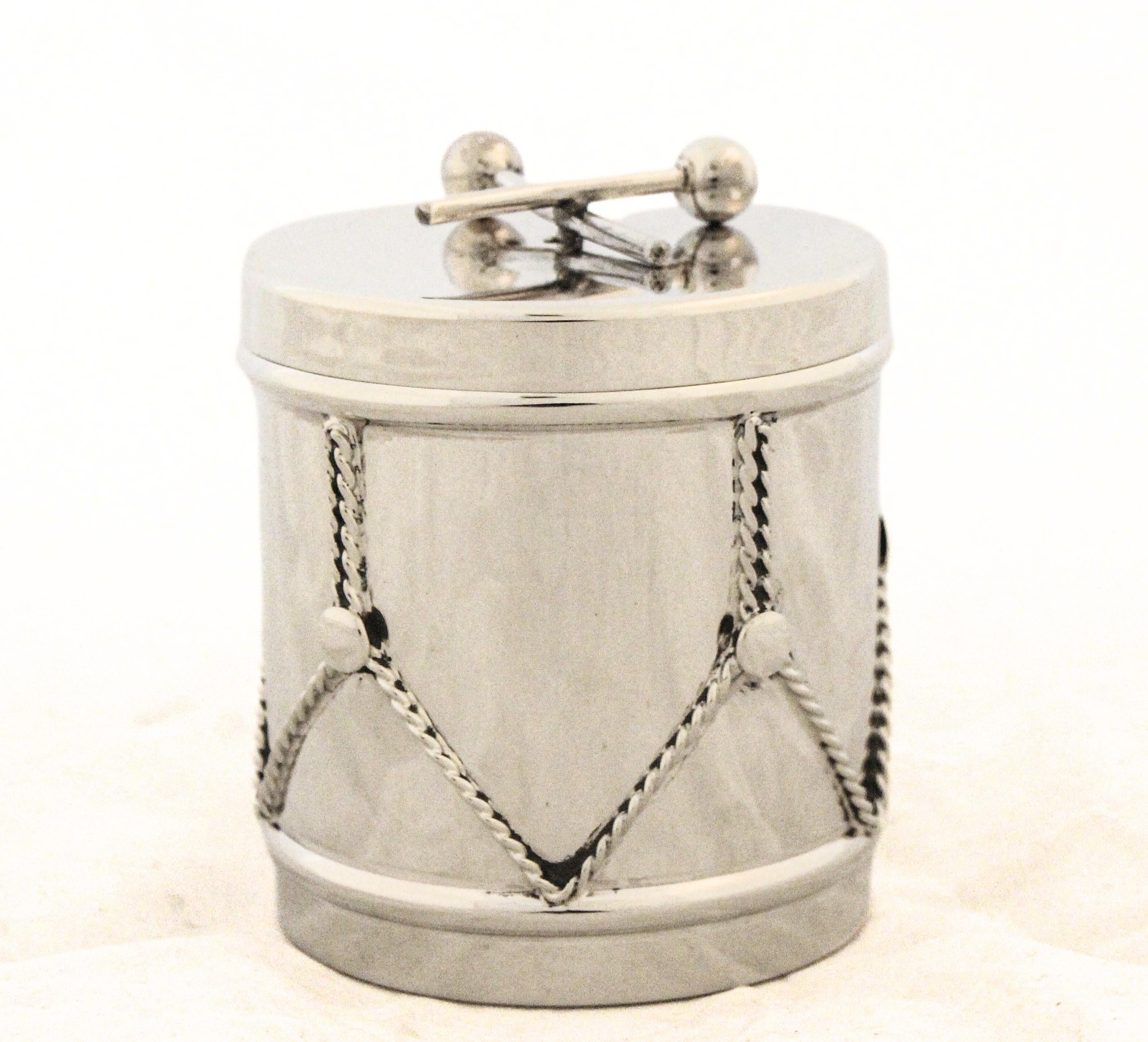 Dieses exquisite Gefäß aus Sterlingsilber ist kunstvoll in der Form einer Trommel gestaltet und mit komplizierten Details an den Seiten versehen, die die Spannseile einer traditionellen kleinen Trommel nachahmen. Der Deckel wird von einem Paar