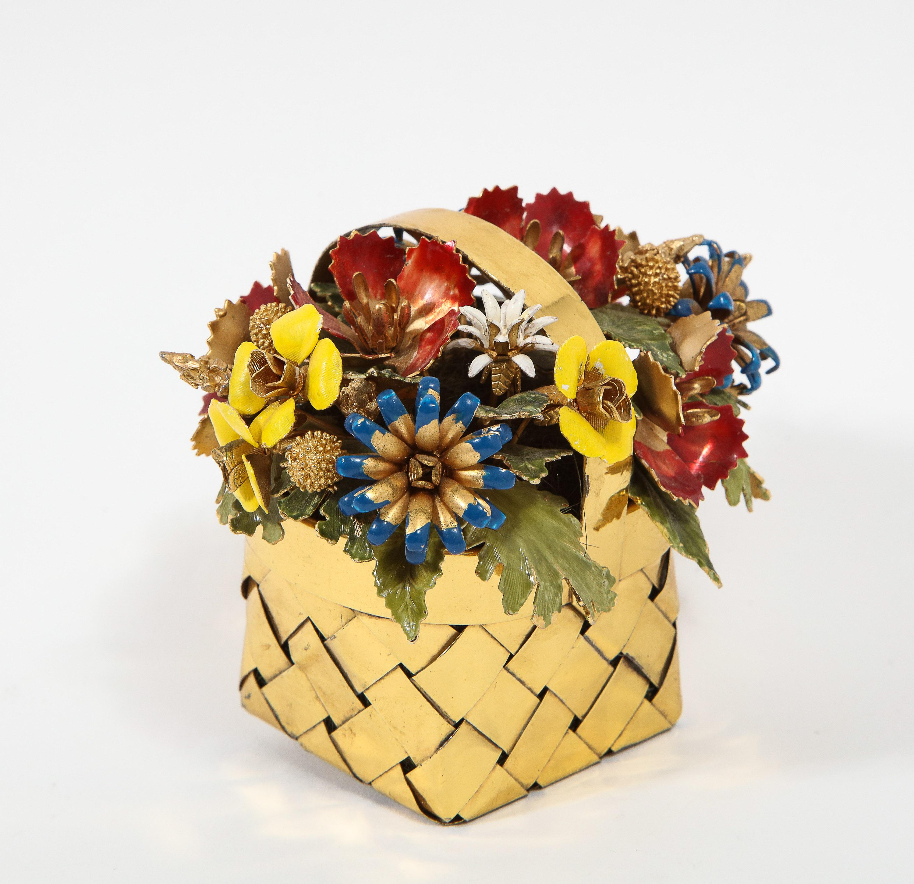 A silver gilt and enamel table ornament basket by Cartier, circa 1950.

Designed by Jane Hutcheson for Cartier.

Modelled as a basket of flowers, the woven silver-gilt punnet filled with a spray of various enamelled flowers, buds and leaves.