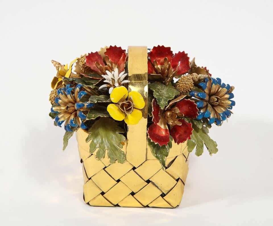 A silver gilt and enamel table ornament basket by Cartier, circa 1950.  

Designed by Jane Hutcheson for Cartier.  

Modelled as a basket of flowers, the woven silver-gilt punnet filled with a spray of various enamelled flowers, buds and leaves.  