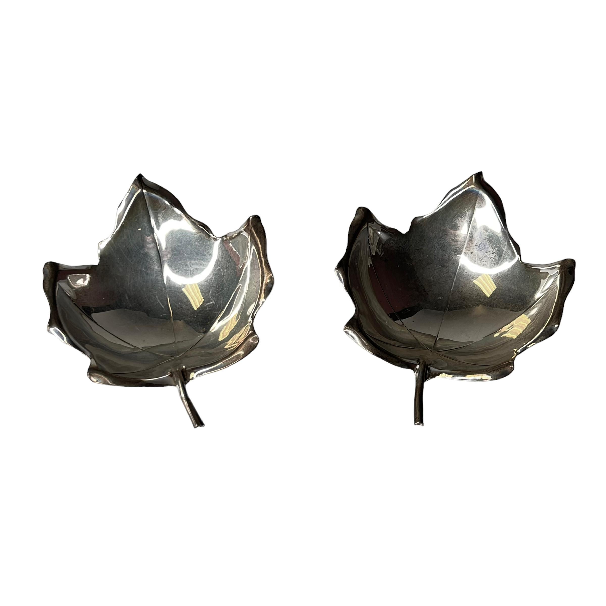 Our pair of sterling silver dishes in the form of maple leaves are raised on three ball shaped feet and come with their original gift case. Each approximately 3.5 by 4.5 by 1 1/18 inches. Case 9 1/8 by 5 by 1 7/8 inches. Each in good condition.