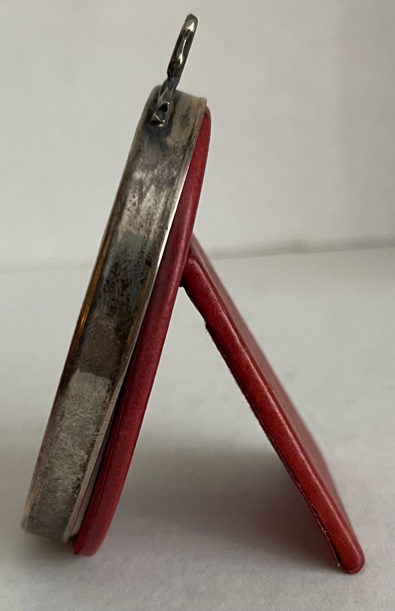 Small sterling silver oval picture frame by Cartier. Center bow detailing. Red leather easel back. 
Includes box and dust bag. Stamped on the underside.