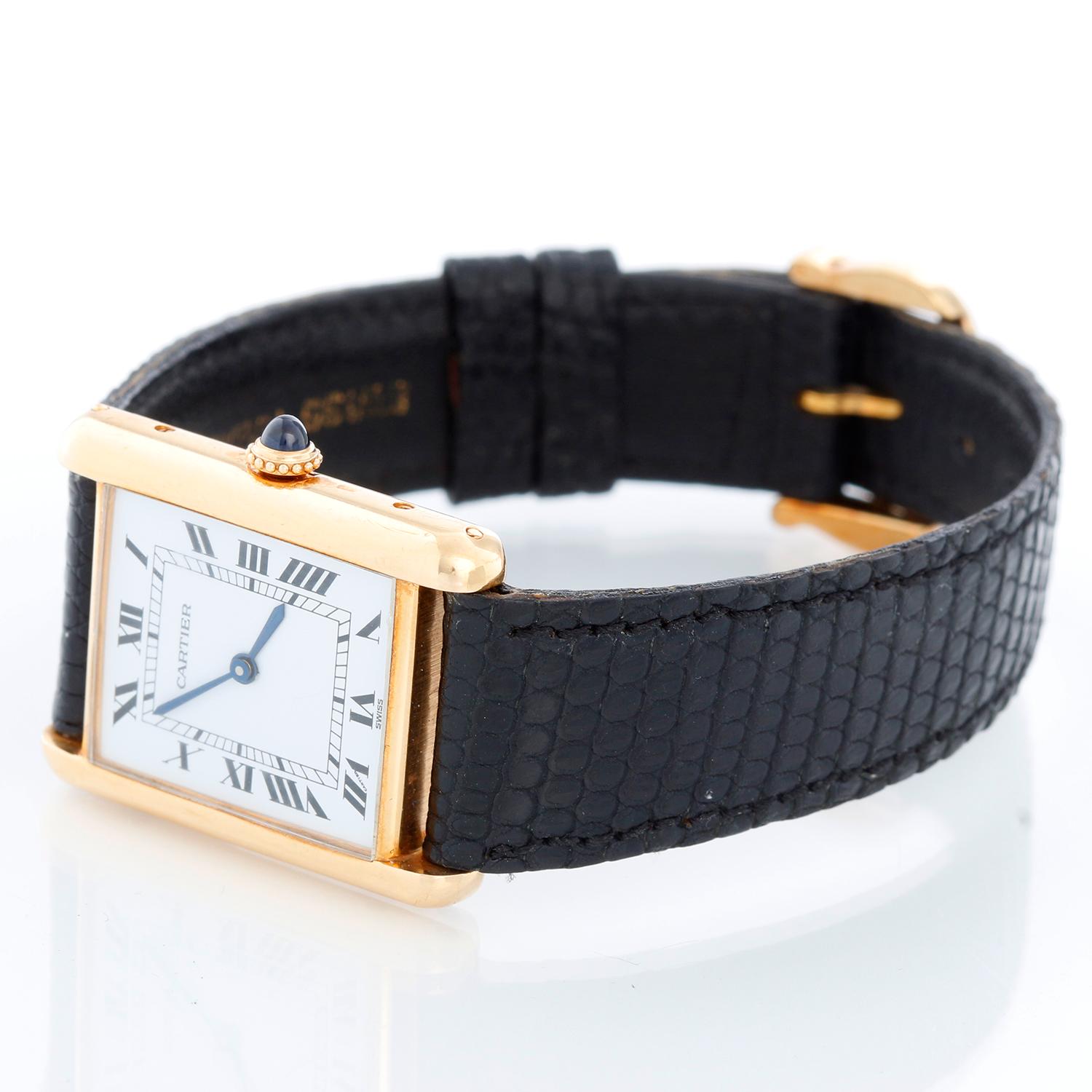 Cartier Tank 18k Gelbgold Damenuhr - Handaufzug. 18K Gelbgold ( 28 x 31 mm ) mit Inschrift auf dem Gehäuseboden. Weißes Zifferblatt mit schwarzen römischen Ziffern. Schwarzes Armband mit Cartier-Tang-Schließe. Pre-owned mit Cartier-Box.