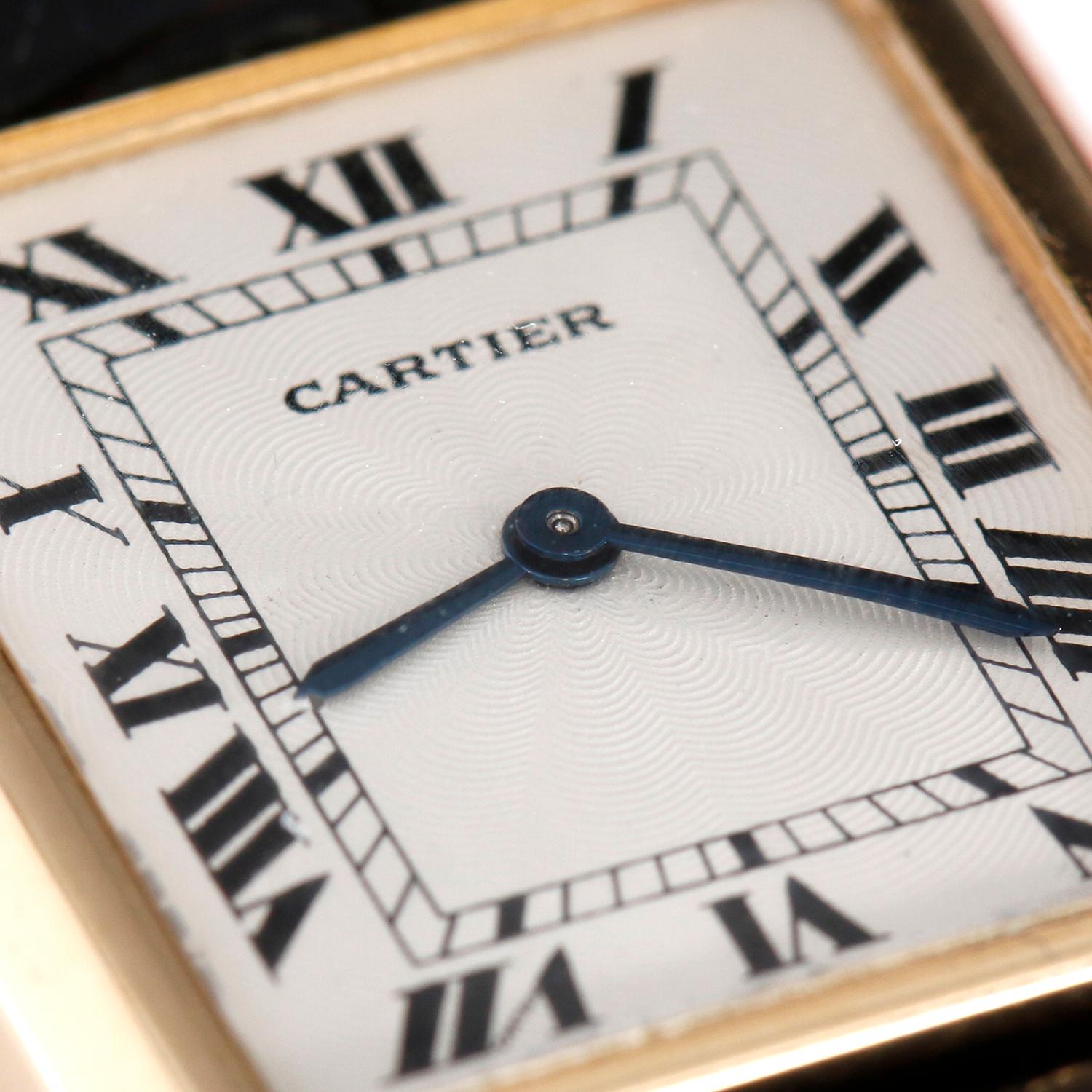 Cartier Tank 18K Yellow Ladies Watch - Manual winding. Tank. 18k yellow gold case back (24mm x 30mm). White dial with black Roman numerals. Black Cartier strap with Cartier tang buckle. Pre-owned with Cartier Pouch.


