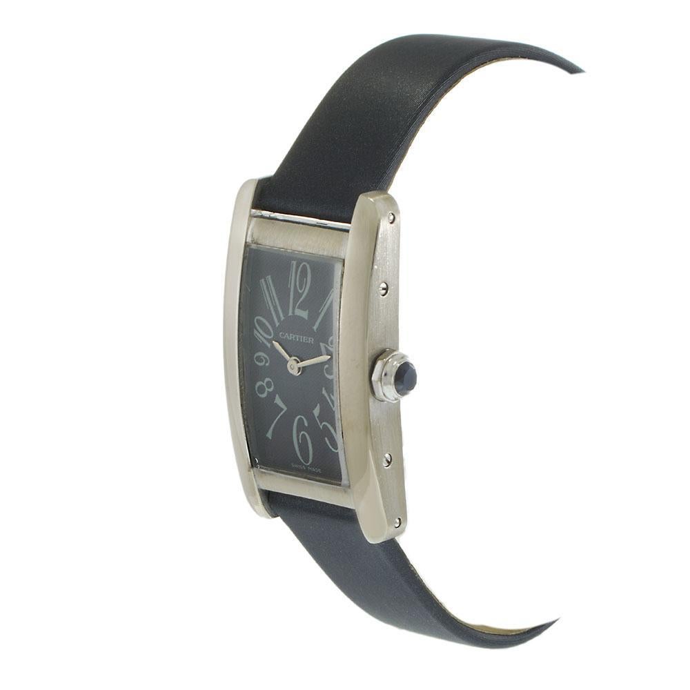 Pre-owned Cartier Tank Américaine ref. W26019L1, featuring a 19 x 35mm 18KT white gold case with a curved profile. The striking blue dial displays bold Arabic numeral hour markers and steel sword-shaped hands. Powered by a Cartier quartz movement