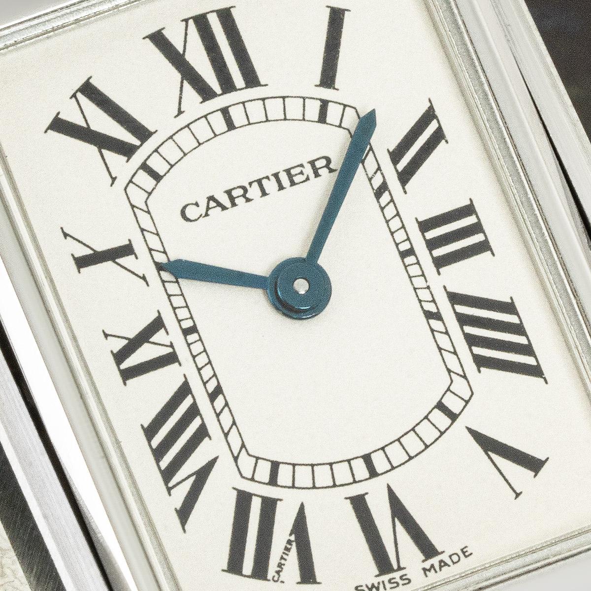 A 24mm stainless steel Tank Basculante by Cartier. Featuring a silver dial with roman numerals, blued steeled sword-shaped hands, a secret Cartier signature at VII and a stainless steel bezel. The watch also includes an engraving on the reversible