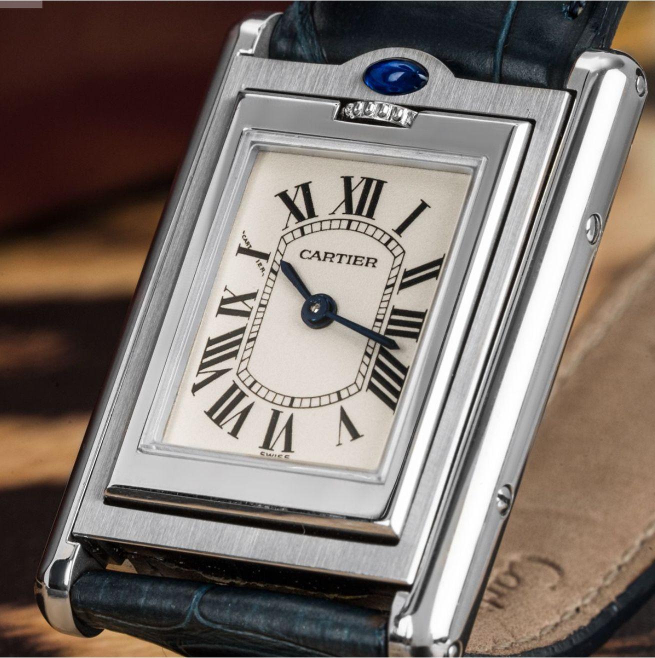 A Stainless Steel Tank Basculante wristwatch. Featuring a silver reversible dial with roman numerals with blued steeled sword shaped hands, a secret Cartier signature at X and a stainless steel bezel.

Fitted with a scratch-resistant sapphire