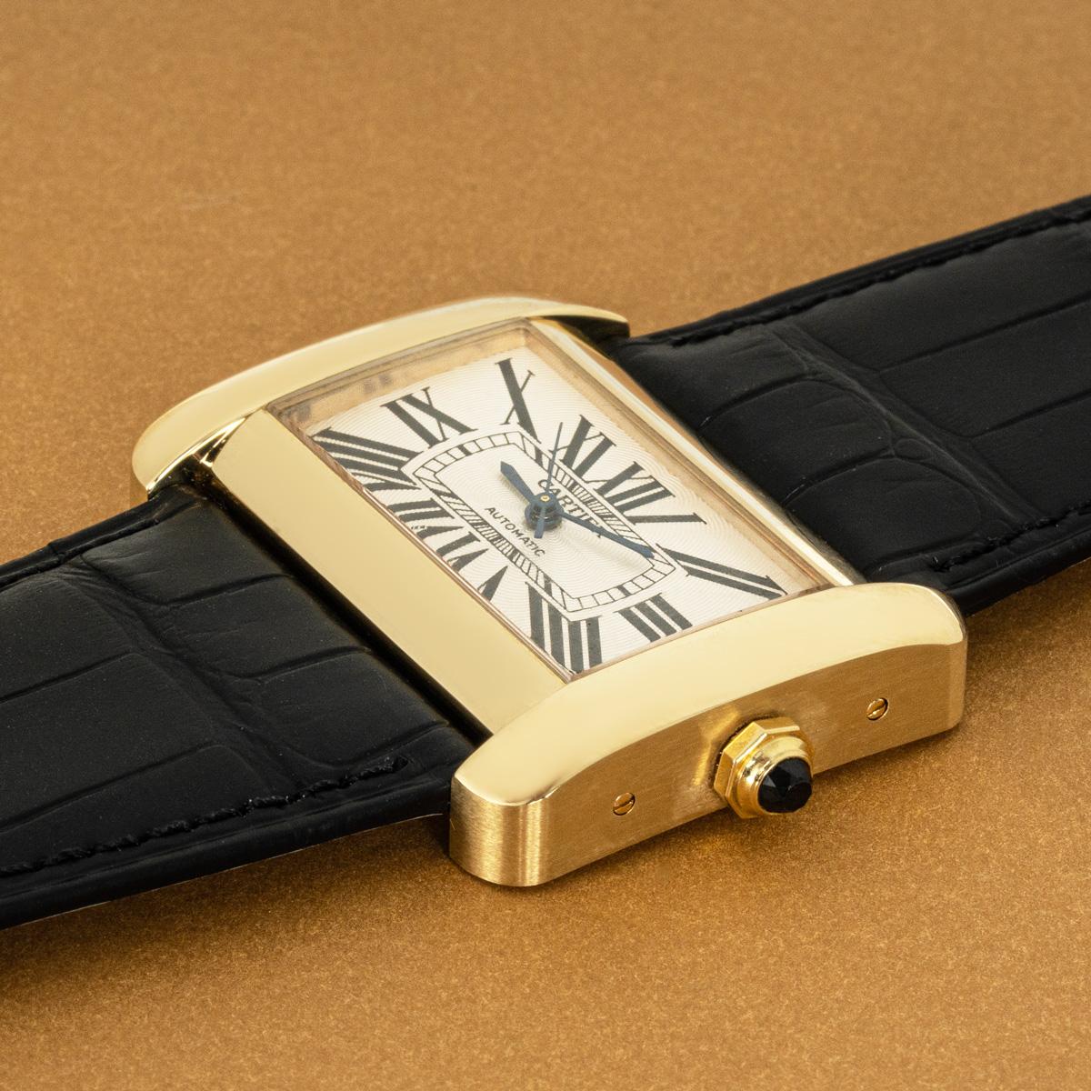 A Cartier Tank Divan XL in yellow gold. Features a silver dial with Roman numerals, blued-steel sword-shaped hands and Cartier's secret signature at V of VII.

Equipped with a new Cartier black leather strap that comes with a Cartier yellow gold pin