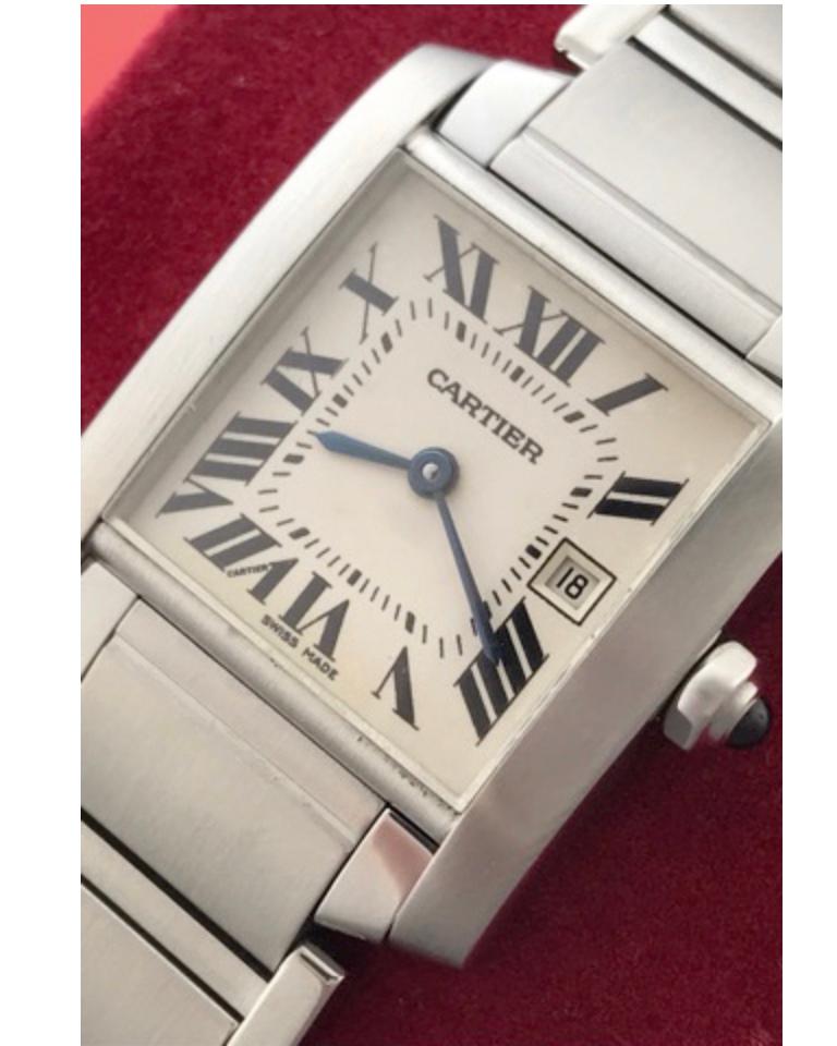 Charming and timeless. This beautiful Cartier Tank Française is in gorgeous condition. This watch features stainless steel construction. The dial is a silver textured dial that features black Roman numerals. The crown is topped with a blue sapphire