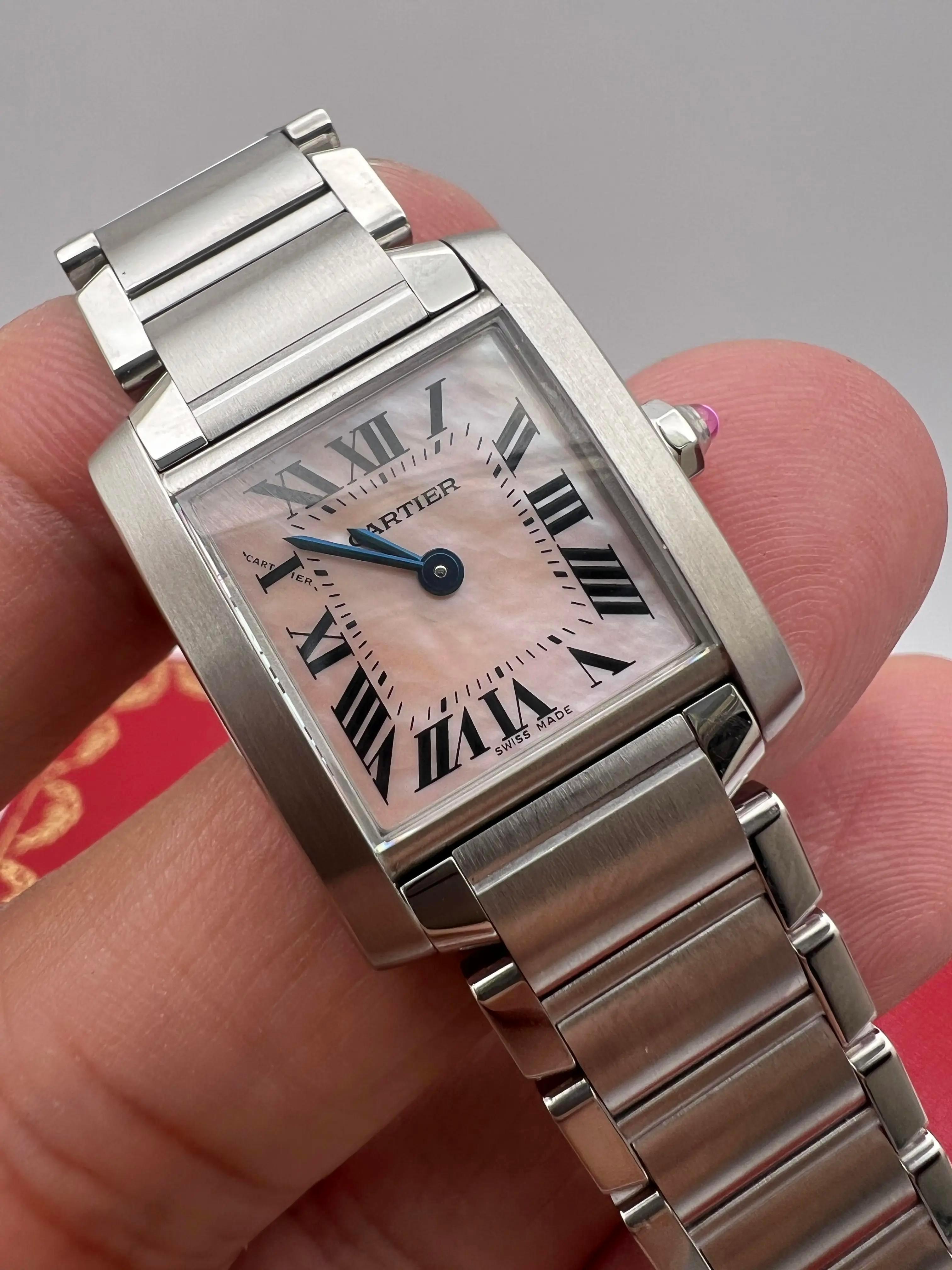 The Cartier Tank Française Small (ref. W51028Q3) is a graceful embodiment of Cartier's iconic elegance with a modern feminine touch. Crafted in polished stainless steel, this petite 20 × 25 mm rectangular case houses a delicate pink mother-of-pearl