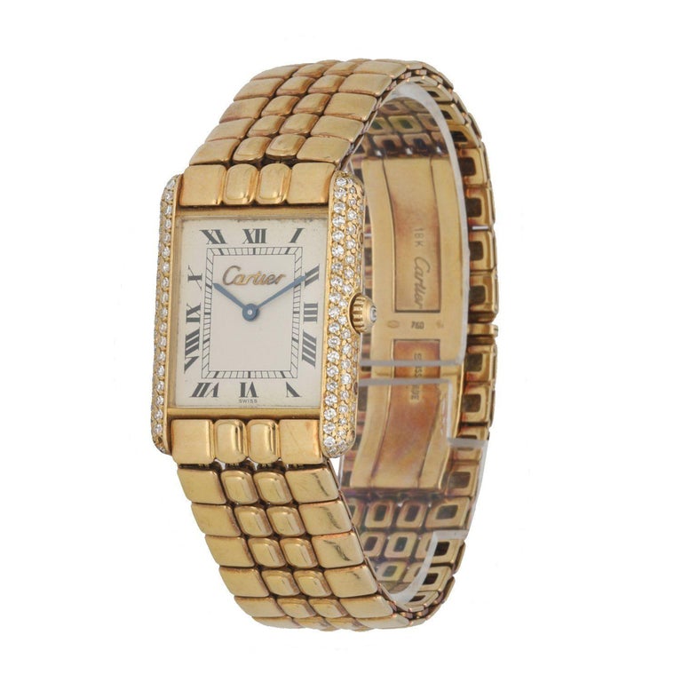 Cartier Tank Louis ladies watch. 23MM 18K yellow gold case with factory diamond bezel. Of-White dial with blue hands and Roman numeral hour marker. Minute marked in the inner dial. 18K yellow gold Vintage bracelet with hidden clasp. Will fit up to