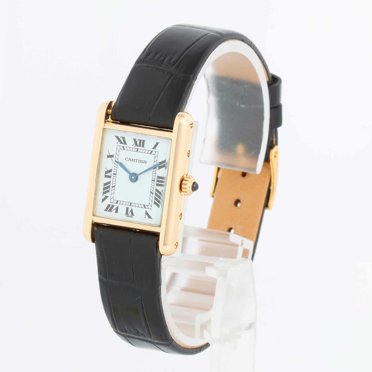 Cartier Tank Louis Ladies 18k Yellow Gold Quartz Watch - Quartz. 18k Yellow Gold case; blue sapphire cabochon in crown (20.5mm x 28mm). White dial with black Roman numerals. Black strap band with tang buckle. Pre-owned with Custom box.