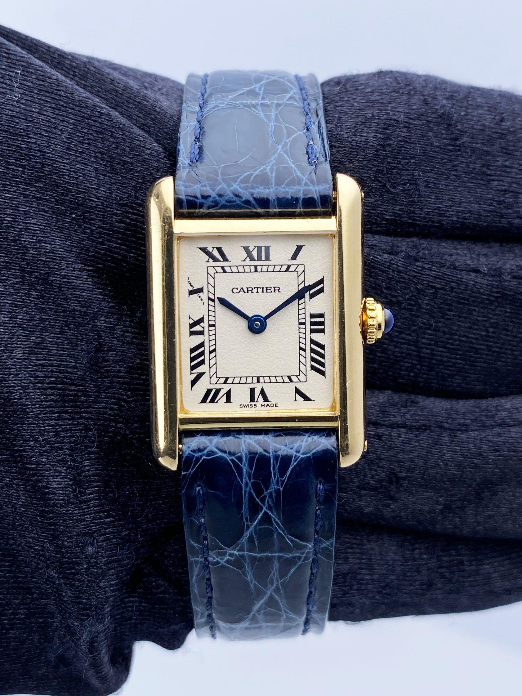 Cartier Tank Louis W1512753 Ladies Watch. 21mm 18K yellow gold case. Off-White dial with blue hands and black Roman numeral hour markers. Minute markers on the inner dial. Blue leather strap with 18K yellow gold buckle. Will fit up to a 6-Inch