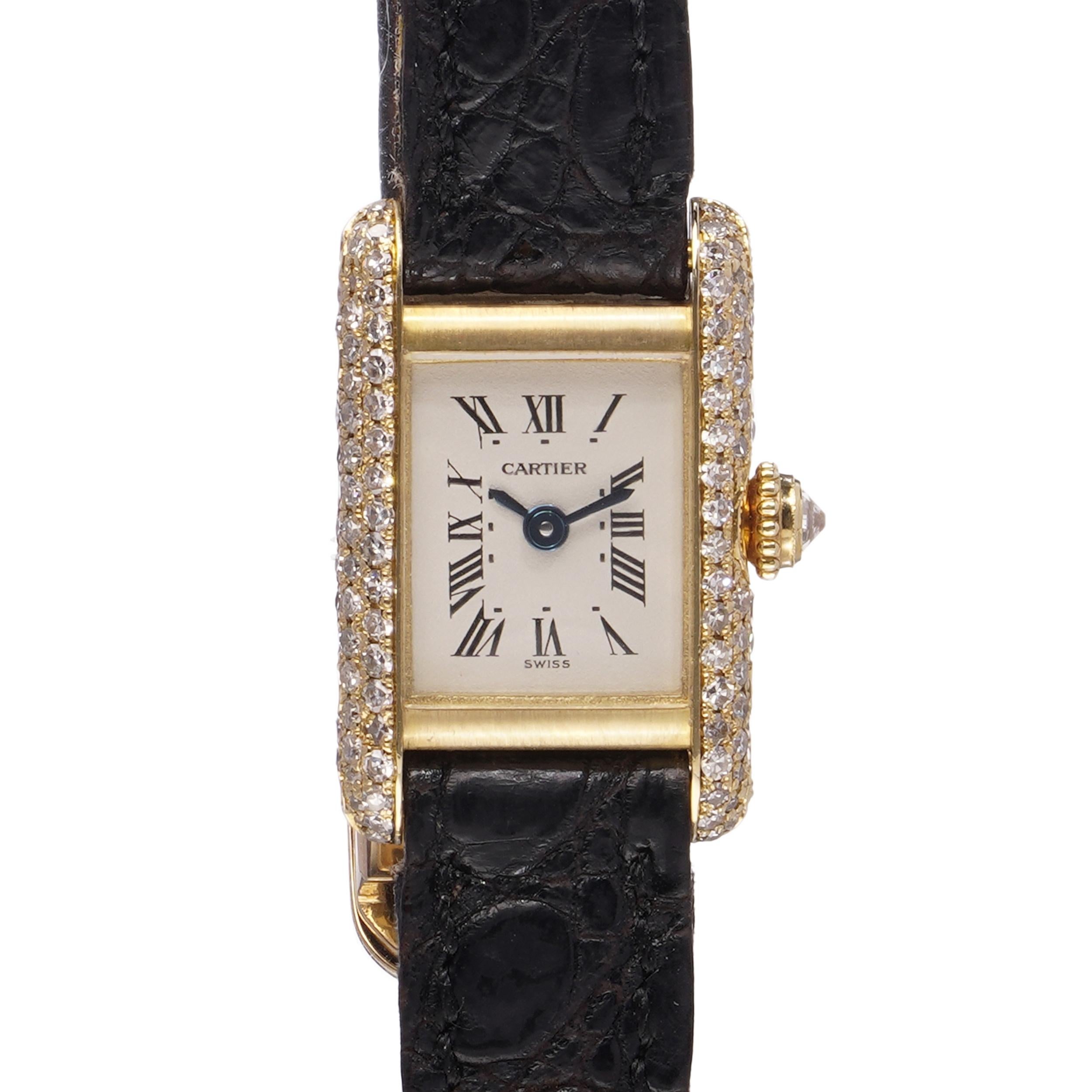 Cartier Tank Mini Quartz ladies wristwatch, crafted in 18kt yellow gold with factory set diamonds. Featuring a rectangular case framed by round brilliant cut diamonds along both sides and the crown. The cream dial displays Roman numerals with blued