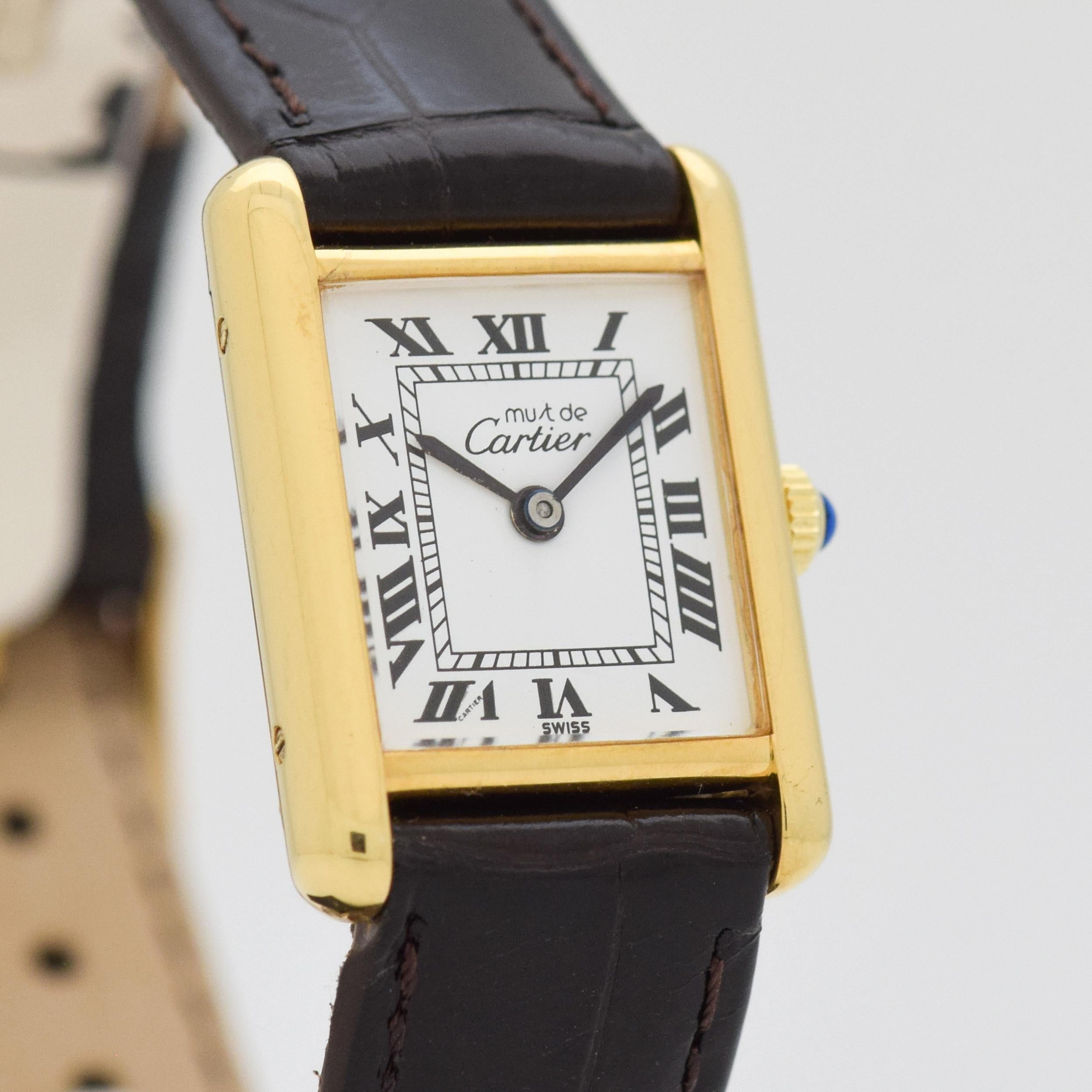 1990's era Cartier Tank Must de Ladies Sized Watch. 18K Yellow Gold Plated over Sterling Silver case. Original, white dial with black-colored, Roman numerals. Case size, 20mm wide. Powered by a 17-jewel, manual caliber ETA movement. Swiss.
