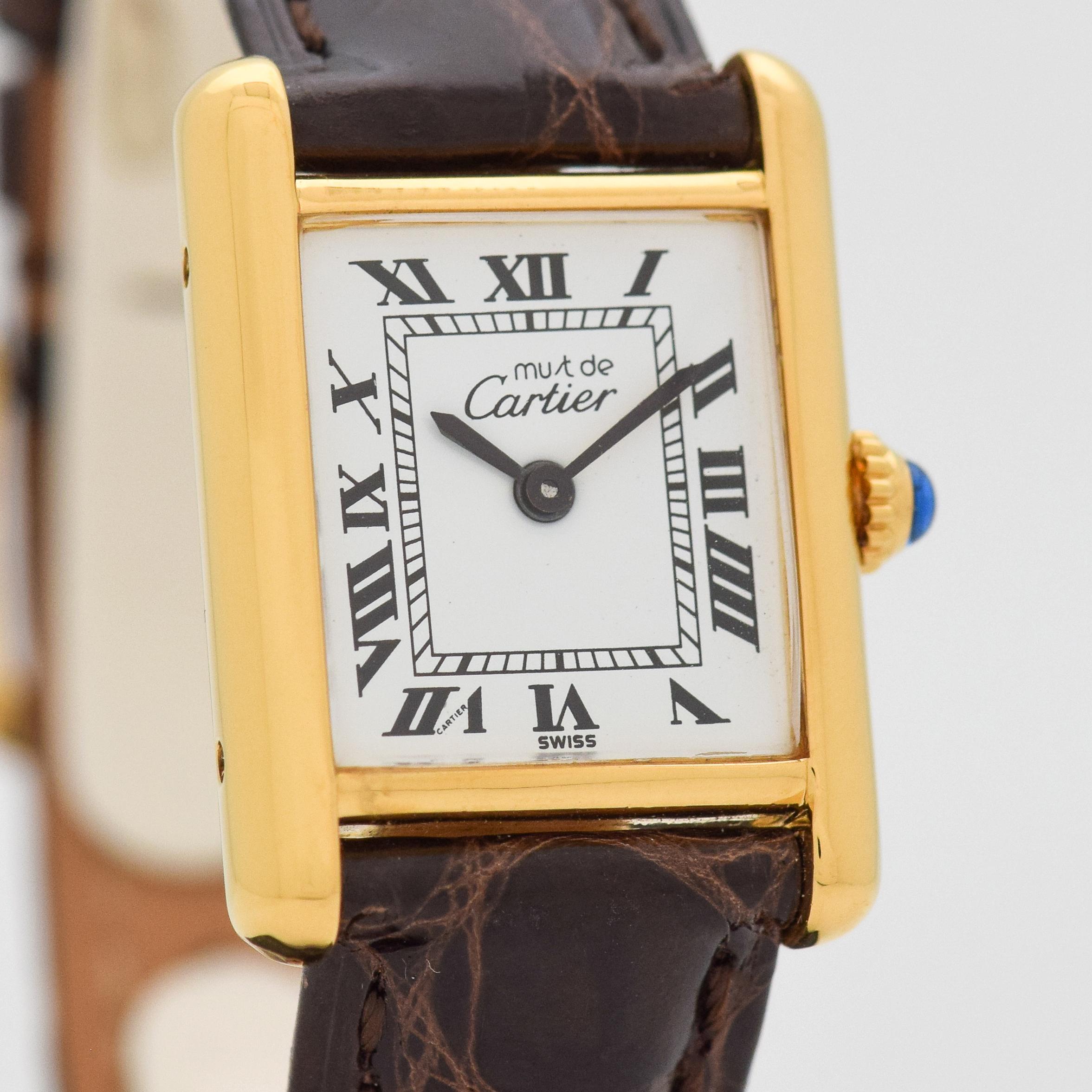 1980's era Cartier Tank Must de Ladies Sized watch. 18K Yellow Gold plated over Sterling Silver. 20mm wide. Powered by a 17-jewel, manual caliber ETA movement. Equipped with a Glossy, Dark Chocolate-colored Crocodile watch strap. Triple Signed.
