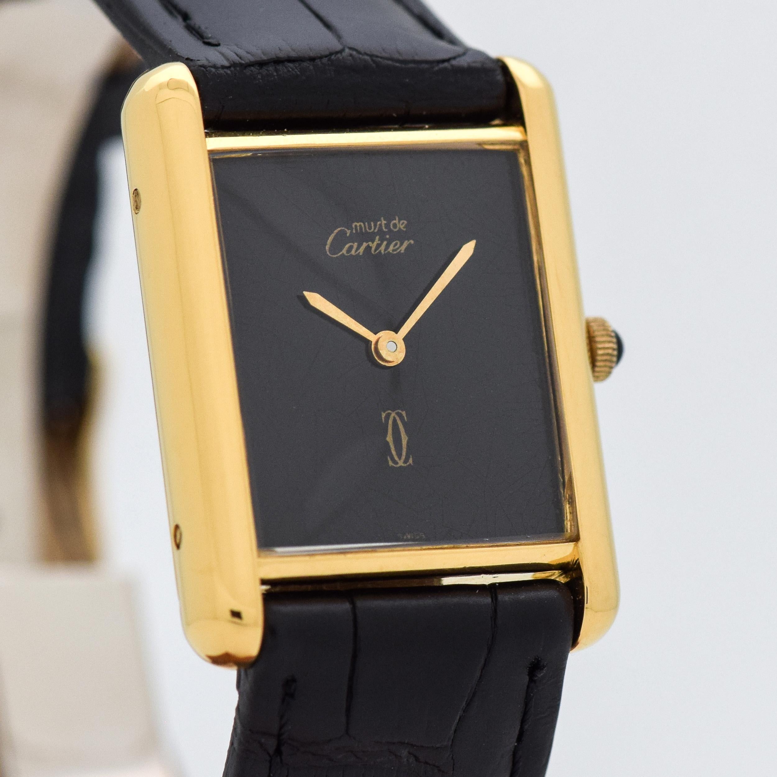 1990's Vintage Cartier Standard Men's Size Must de Cartier Tank 18k Yellow Gold Plated Over Sterling Silver watch wit Original Black Dial. Triple Singed. 23mm x 27mm lug to lug (0.91 in. x 1.06 in.) - 17 jewel, manual caliber ETA movement. Suitable