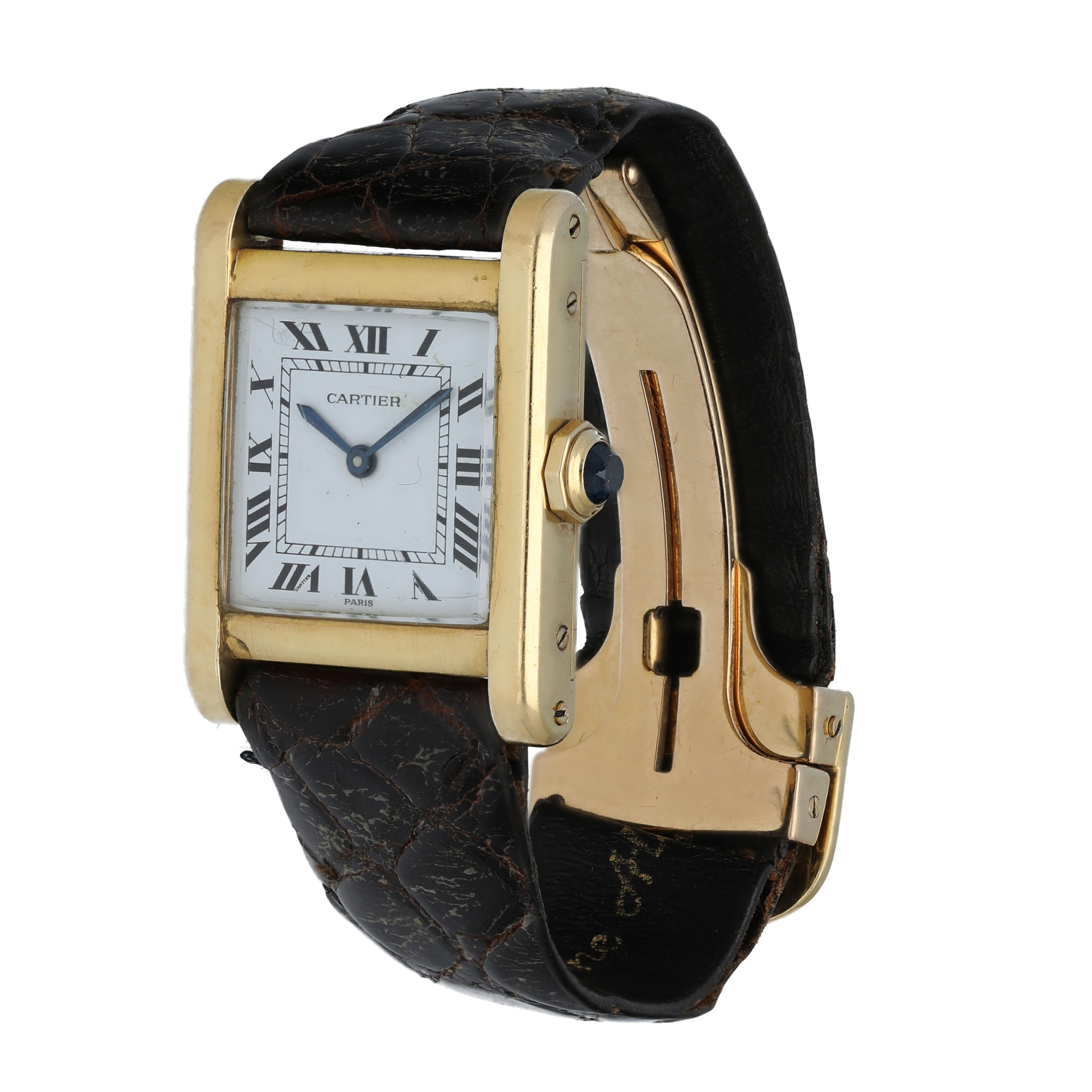 Cartier Tank Ladies Watch. 
23mm 18k Yellow gold case. 
White dial with blue steel hands and Roman numeral hour markers. 
Minute markers on the inner dial. 
Leather Alligator Strap with 18k rose gold Deployment. 
Will fit up to a 5-inch wrist.