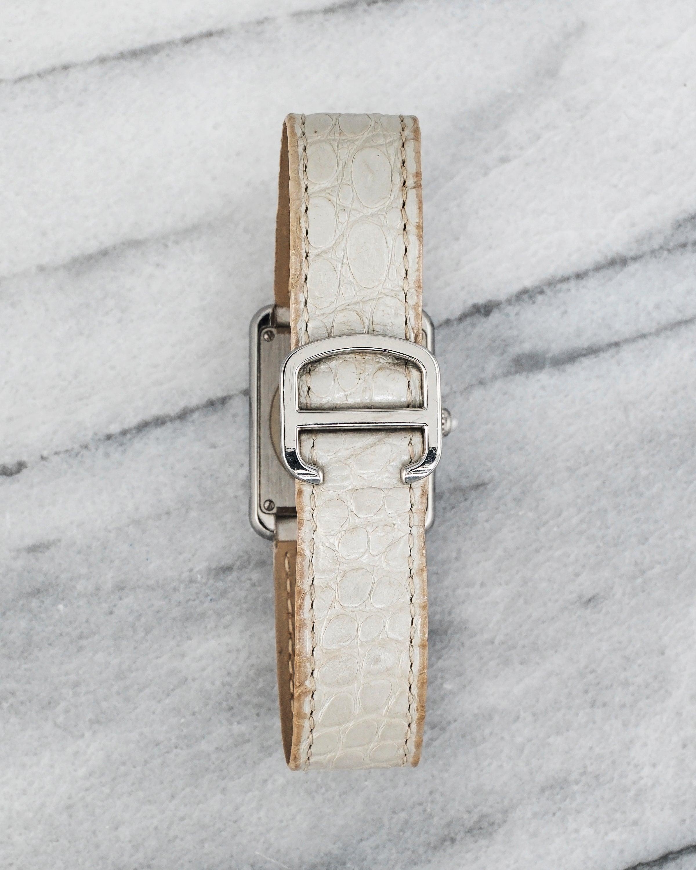 Aquí tienes un Cartier Tank Solo referencia 2716 cuarzo con esfera monograma plateada de la década de 2000. Las medidas incluyen una caja de 24x31 mm y un ancho de orejeta de 18 mm. Con su correa original de cuero blanco y hebilla desplegable de