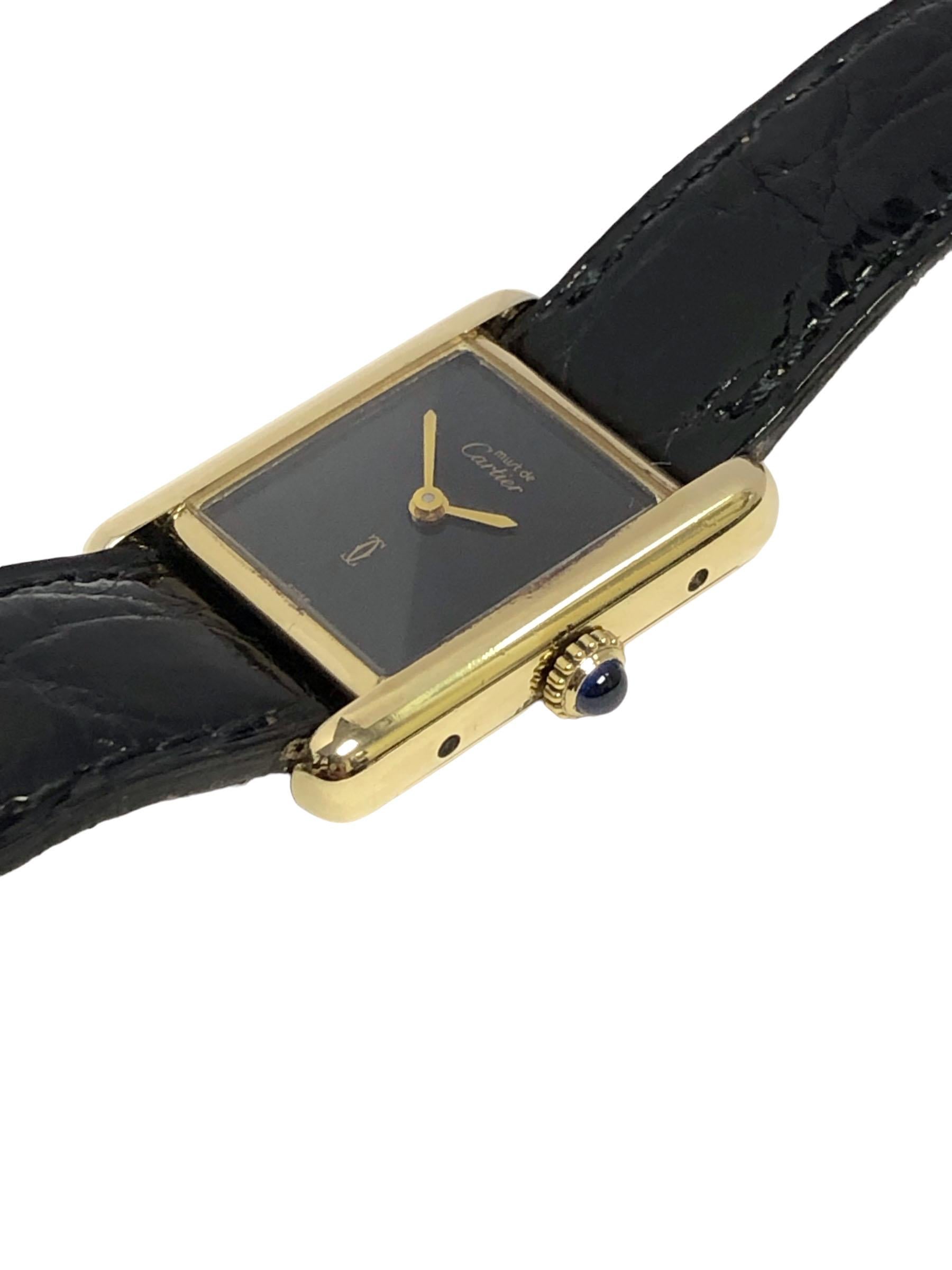 Circa 1990 Montre-bracelet Cartier Classic Tank, 28 X 20 M&M. Boîtier 2 pièces Vermeil ( Plaque d'or sur argent sterling ). Mouvement mécanique à remontage manuel, cadran noir avec aiguilles dorées, couronne sertie de saphirs. Bracelet original en