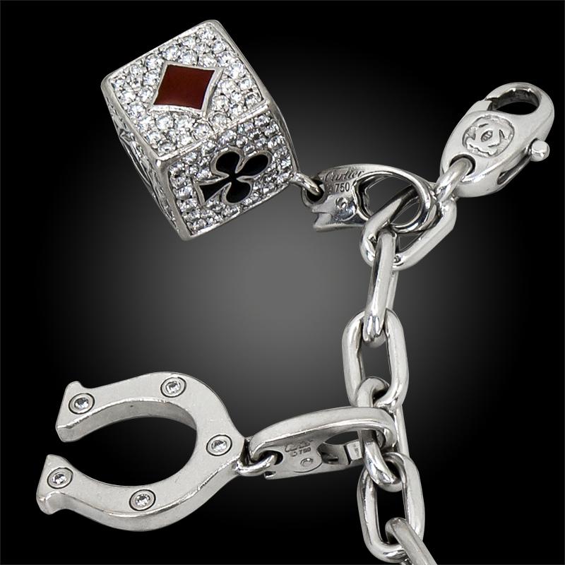 An 18k white gold ten charm bracelet, set with ruby, diamond, and enamel, signed Cartier.
Circa 19980s
approx. 7 1/2″ long
