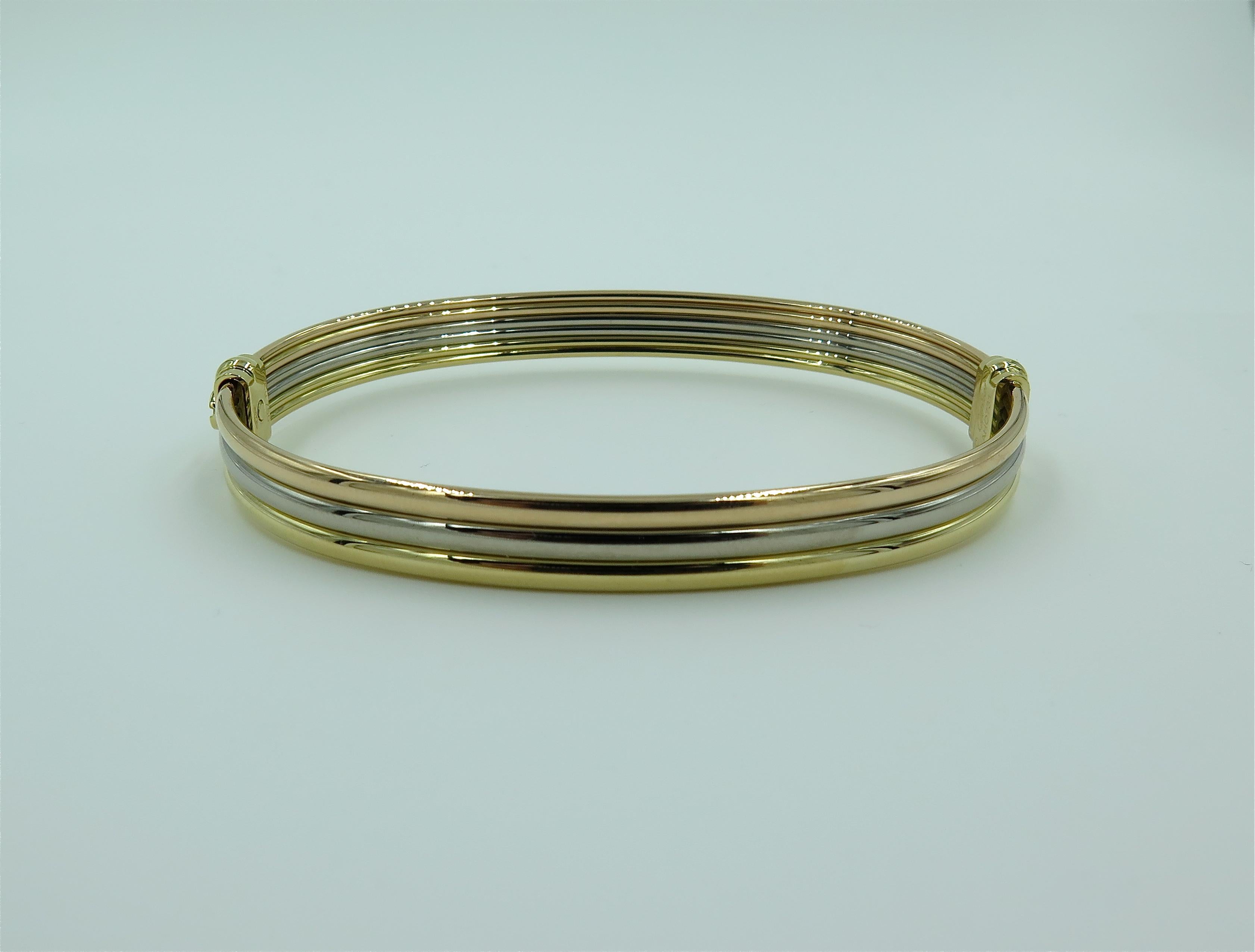 An 18 Tri colored gold bangle. Cartier. Designed as a polished hinged rose, white and yellow gold bangle, joined by a screw closure. Inside measurement is approximately 8 Incas, diameter is approximately 3 inches. Stamped Cartier, numbered AHO731.