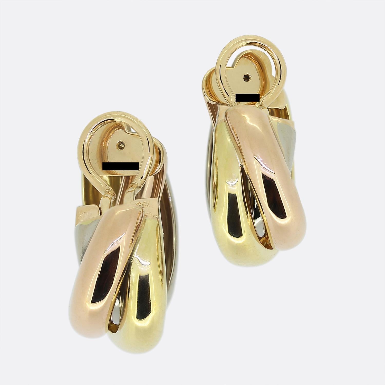 Hier haben wir ein ikonisches Paar Bügelohrringe aus dem Luxusschmuckhaus Cartier. Jeder Ohrring besteht aus drei kontrastierenden Barren aus 18-karätigem Gold, die ineinander verschlungen sind und eine glatte, polierte Oberfläche aufweisen.