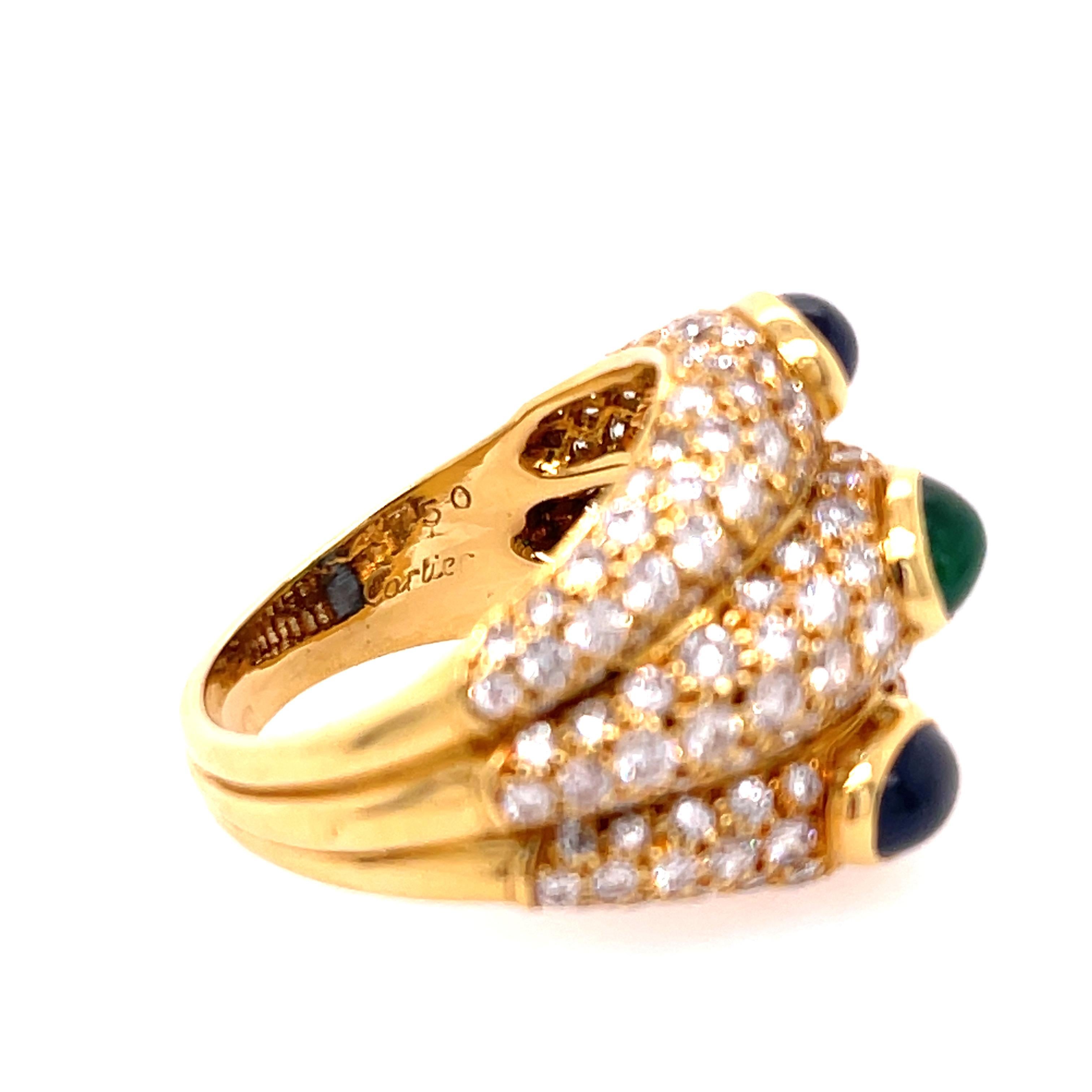 Bague Cartier à trois pavés en or jaune 18 carats. La bague comporte deux cabochons de saphir et un cabochon d'émeraude. Environ 4,25ctw de diamants ronds de taille brillante. Bague taille 7.   

10,5 grammes