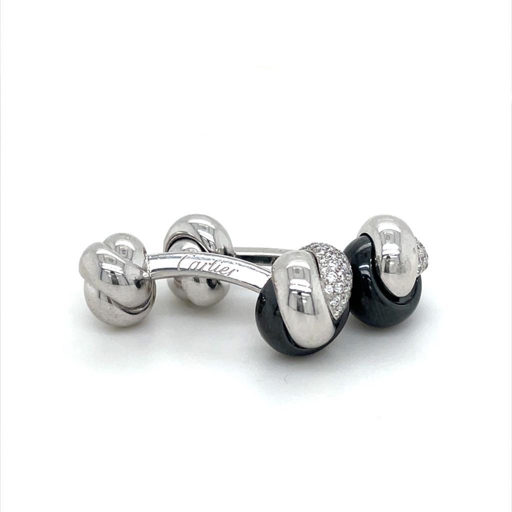 A pair of Cartier Trinity 18 karat white gold, diamond and ceramic knotted cufflinks, circa 2018.

These smart cufflinks feature two intricately detailed knots between T-bar fittings.
One knot of each cufflink is formed as an interwoven design