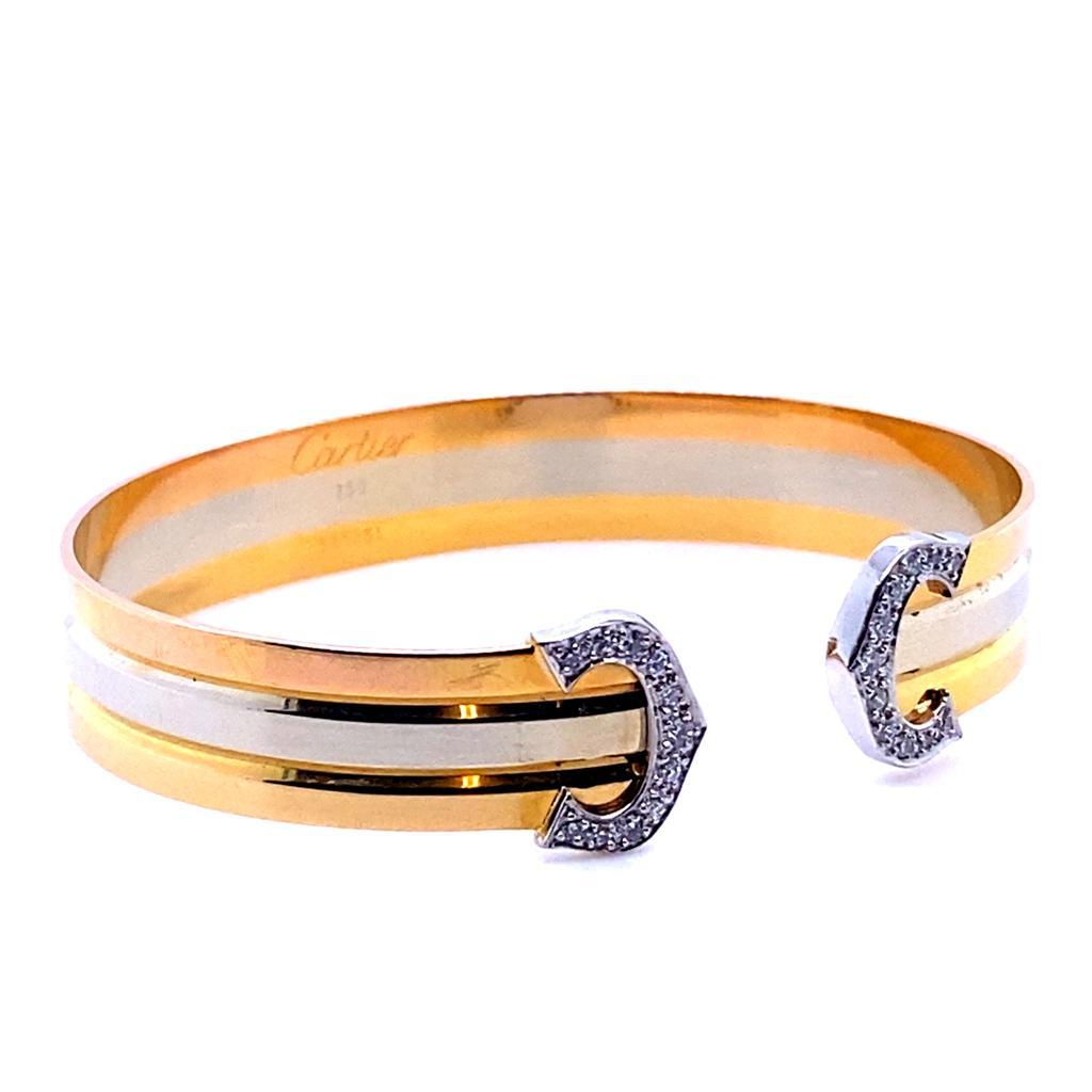 A Cartier Trinity 18 karat yellow white and rose gold cuff bracelet, circa 1990

This classic, wearable Cartier Trinity tri-colour gold open cuff bracelet features two diamond set C's, one terminating either end of the piece.
The twenty two round