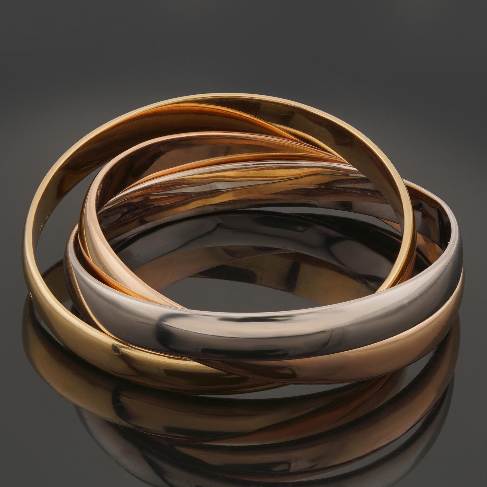 This iconic extra large model bracelet from Cartier's Trinity collection features 3 interconnected bangles crafted in 18k yellow, white, and rose gold. Made in France circa 1990s. Measurements: 0.35