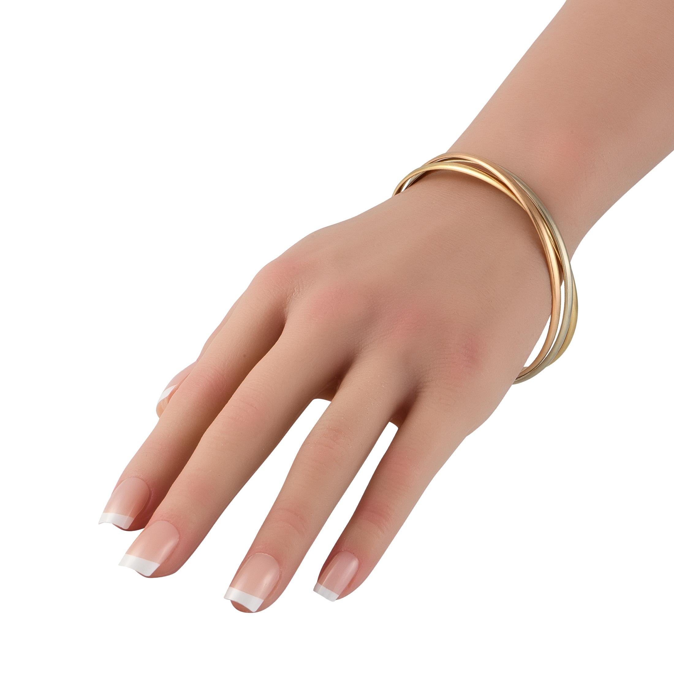 The perfect example of effortless elegance. There is nothing flashy about Cartier's Trinity bangle bracelet, yet its presence is undeniable. This piece features a trio of banglesin yellow gold, white gold, and rose gold. All come with a smooth,
