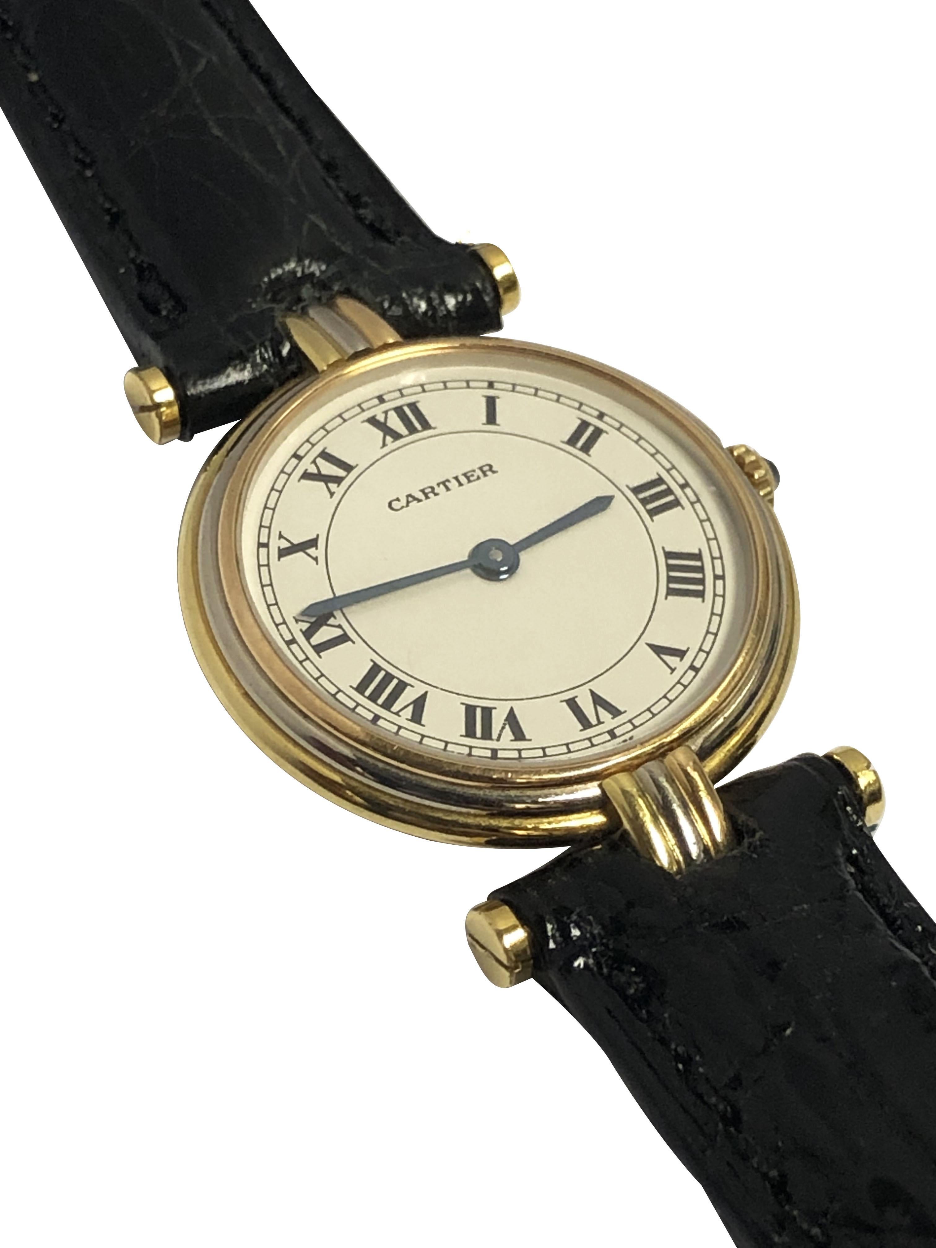 Circa 1990s Cartier 18K Yellow, White and Rose Gold Ladies Trinity Watch. 2 piece 24 MM water resistant case, Quartz Movement, White Dial with Black Roman Numerals and a Sapphire set crown. New Black Crocodile strap with a Cartier Gold Plate Tang