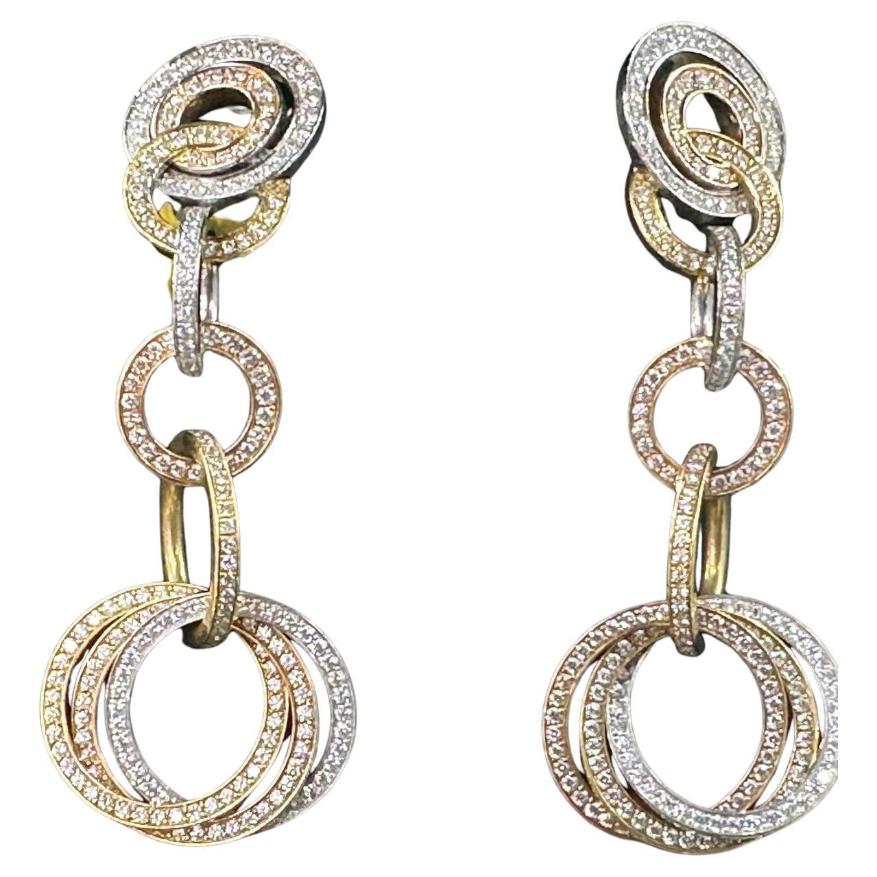 The Cartier Trinity earrings showcase a classic and sophisticated design crafted from 18k tri-colour gold, featuring white, yellow, and rose gold bands. Each earring consists of three interlocking bands that symbolize unity and eternity. The elegant