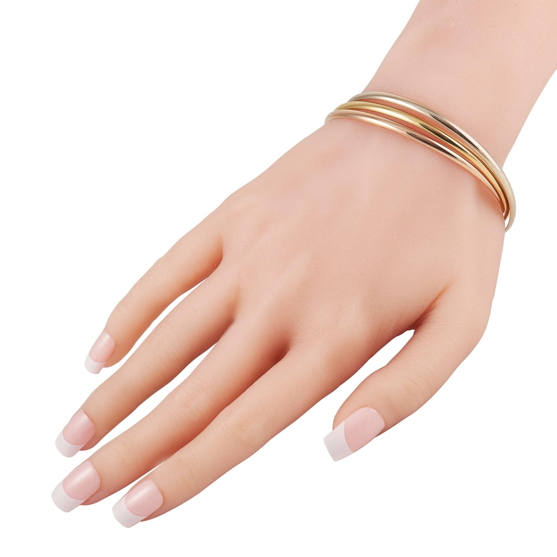 Delivering simple luxury is this Cartier Trinity Bangle Bracelet. It features a trio of slender rigid bangles in 18-karat yellow gold, white gold, and rose gold. With its uncluttered look, minimalist aesthetic, and eternal style, this piece of
