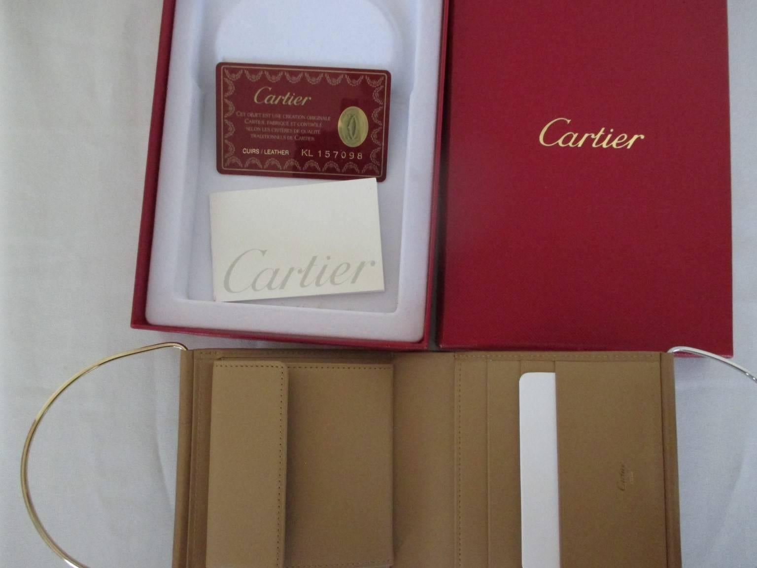 Authentic from Cartier, this is a polished calfskin leather wallet purse with a two tone metal tone handle one silver and one gold in high polished finish. 
 The interior has card pockets, compartments for bills and a coin pocket.
Comes with the