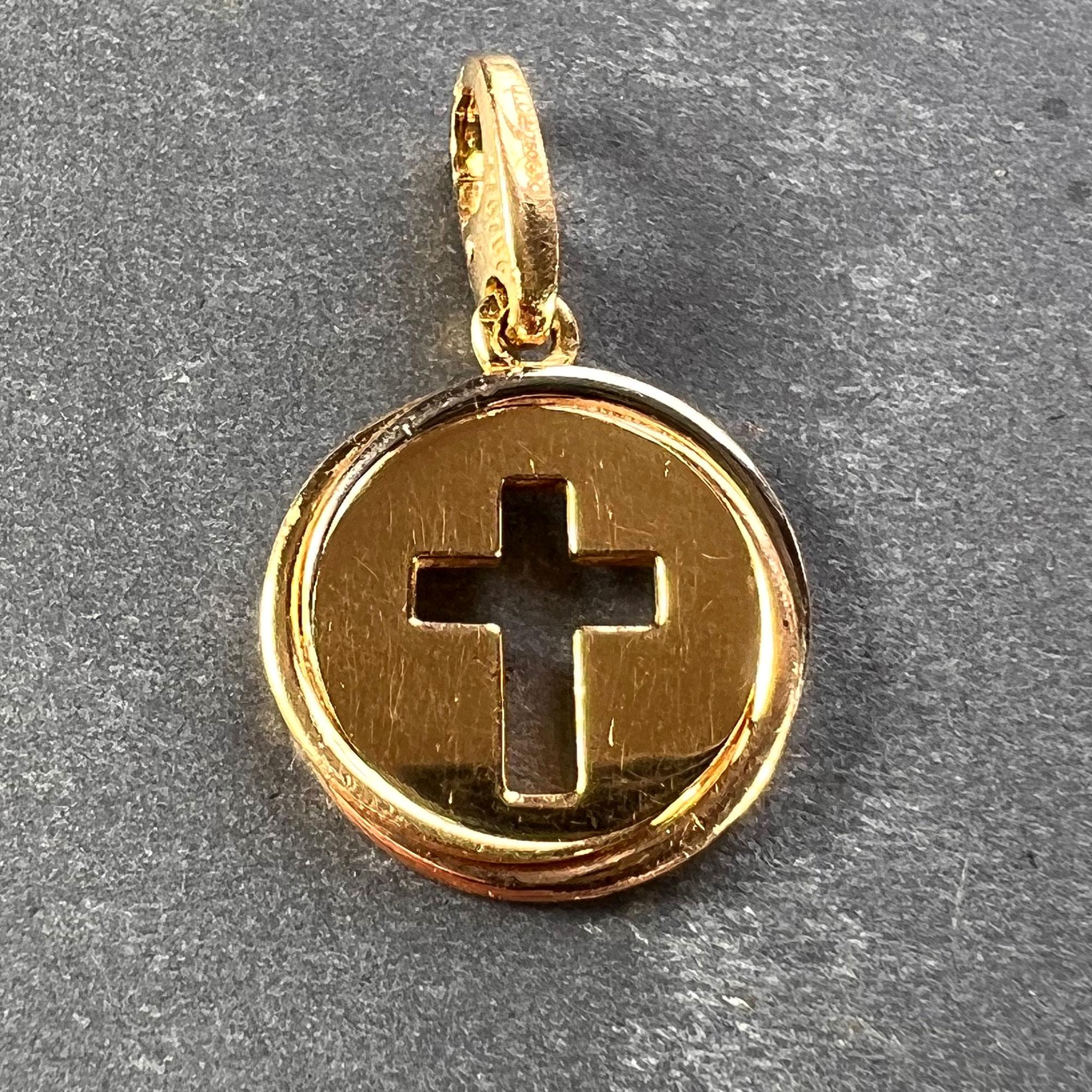 An 18 karat (18K) gold charm pendant designed as a yellow gold disc with a pierced cross motif surrounded by the Trinity style edge of twisted yellow, rose and white gold wires. Signed Cartier, stamped with the eagle’s head for French manufacture