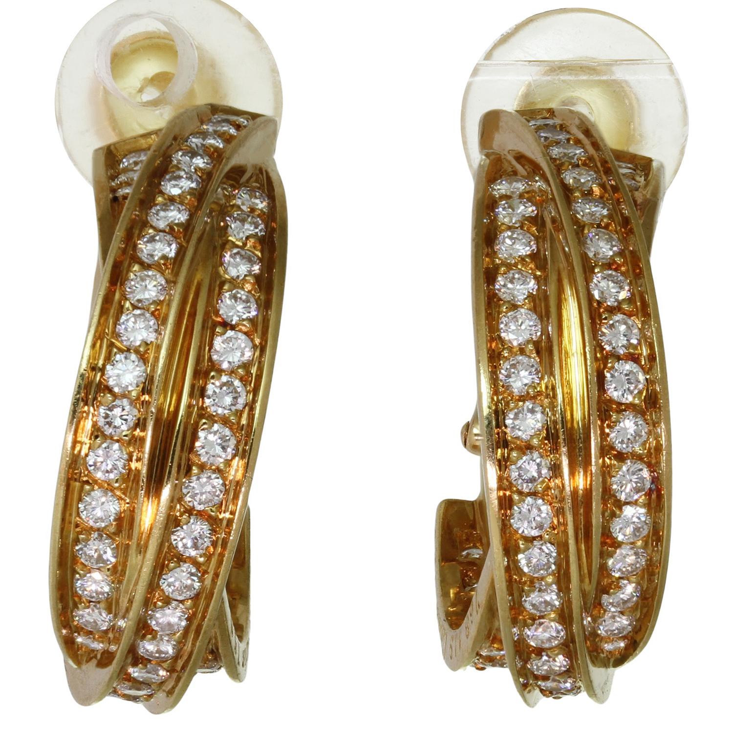 These stunning Cartier earrings from the classic Trinity de Cartier collection feature a hoop lever-back design with three interlocking bands crafted in 18k yellow gold and set with brilliant-cut round diamonds. Made in France circa 2000s.