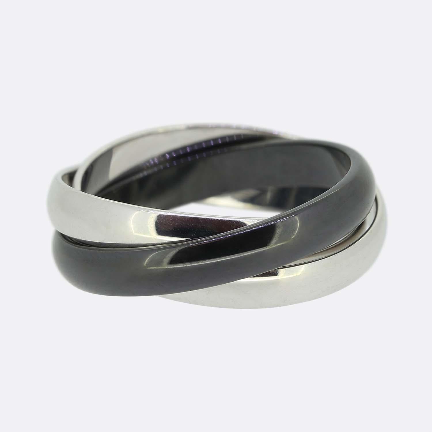 Here we have an 18ct white gold and ceramic trinity ring from the world renowned luxury jewellery house of Cartier. This ring features three interwinding bands. Two 18ct white gold and one in darkened ceramic; the white gold of which has been softly