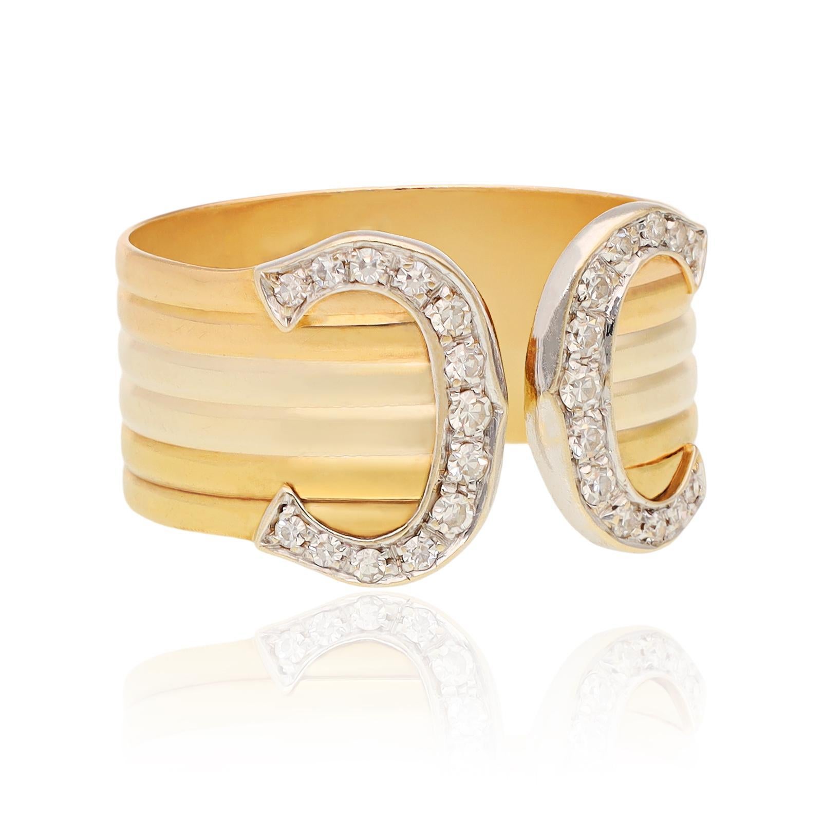 Tre bande piatte di filo d'oro - bianco, giallo e rosa - sono impilate con eleganza per circondare il dito. Il design è sormontato da doppi motivi a C in oro bianco con diamanti taglio brillante. La parte anteriore aperta migliora l'estetica