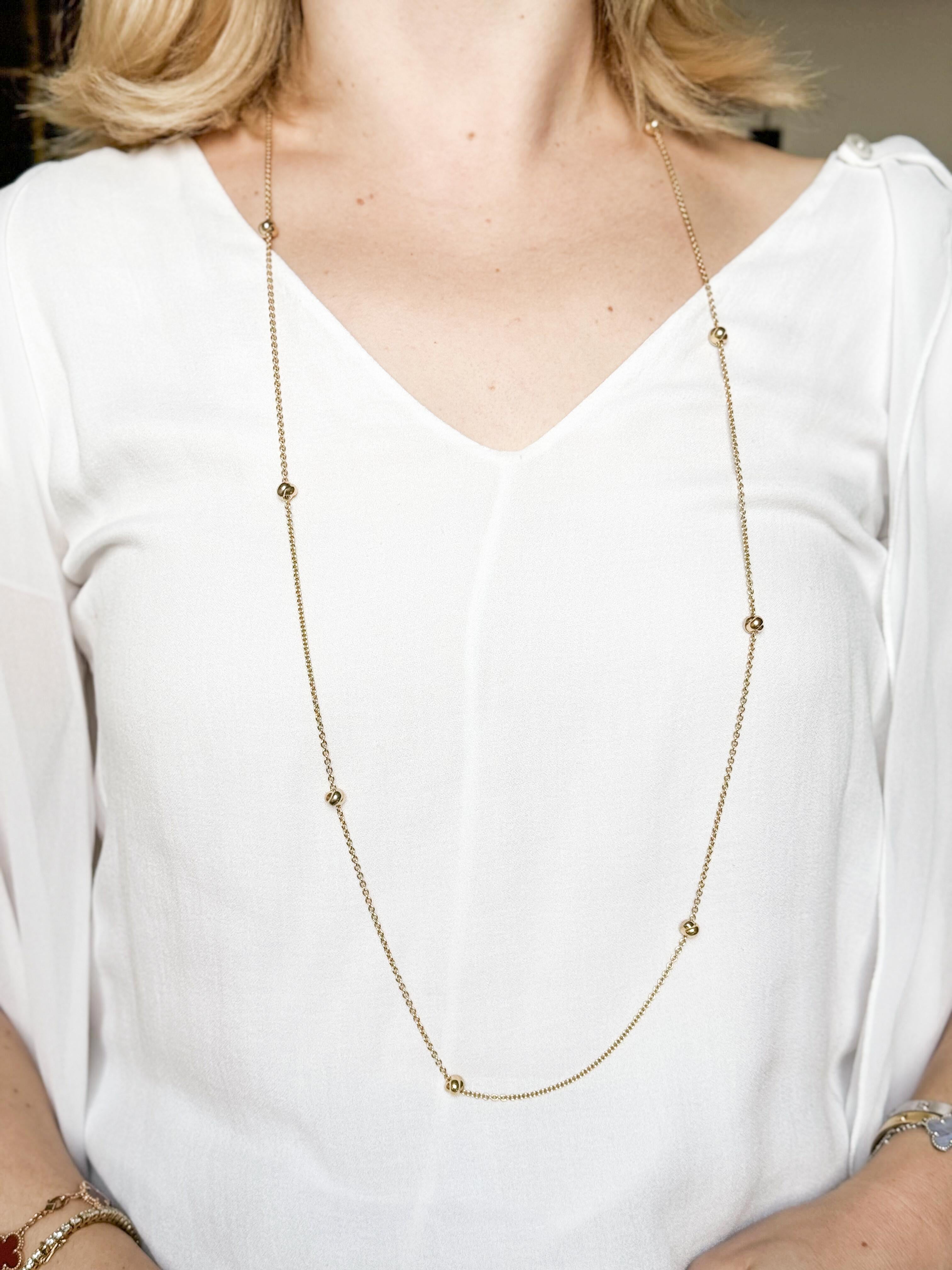 Long 18k gold necklace by Cartier, featuring 9 Trinity knot stations. Necklace is 41.5