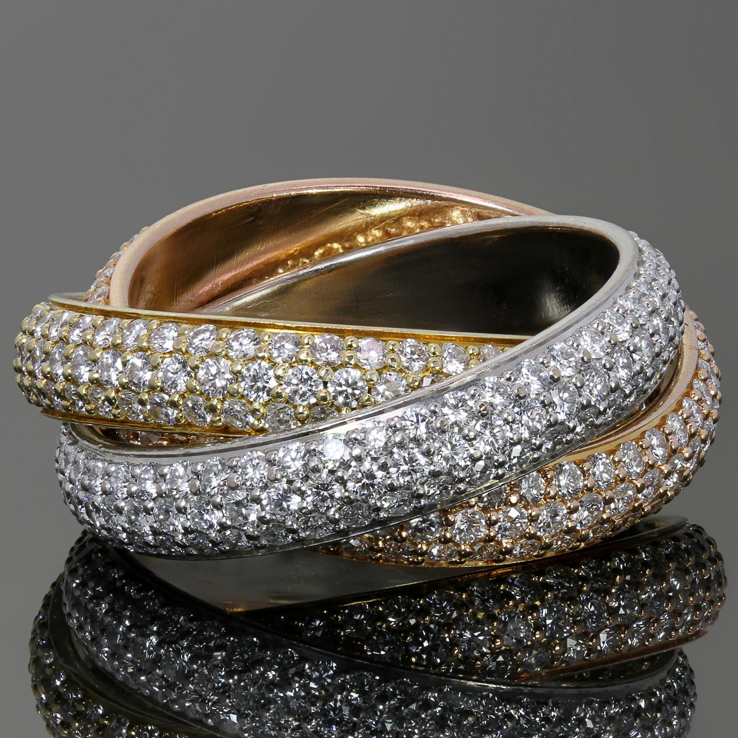 This iconic ring from Cartier's Trinity collection features 3 interconnected bands crafted in 18k yellow, white and rose gold and pave-set with brilliant-cut round F-G VVS2-VS1 diamonds weighing an estimated 2.95 carats. Made in France circa 2000s.