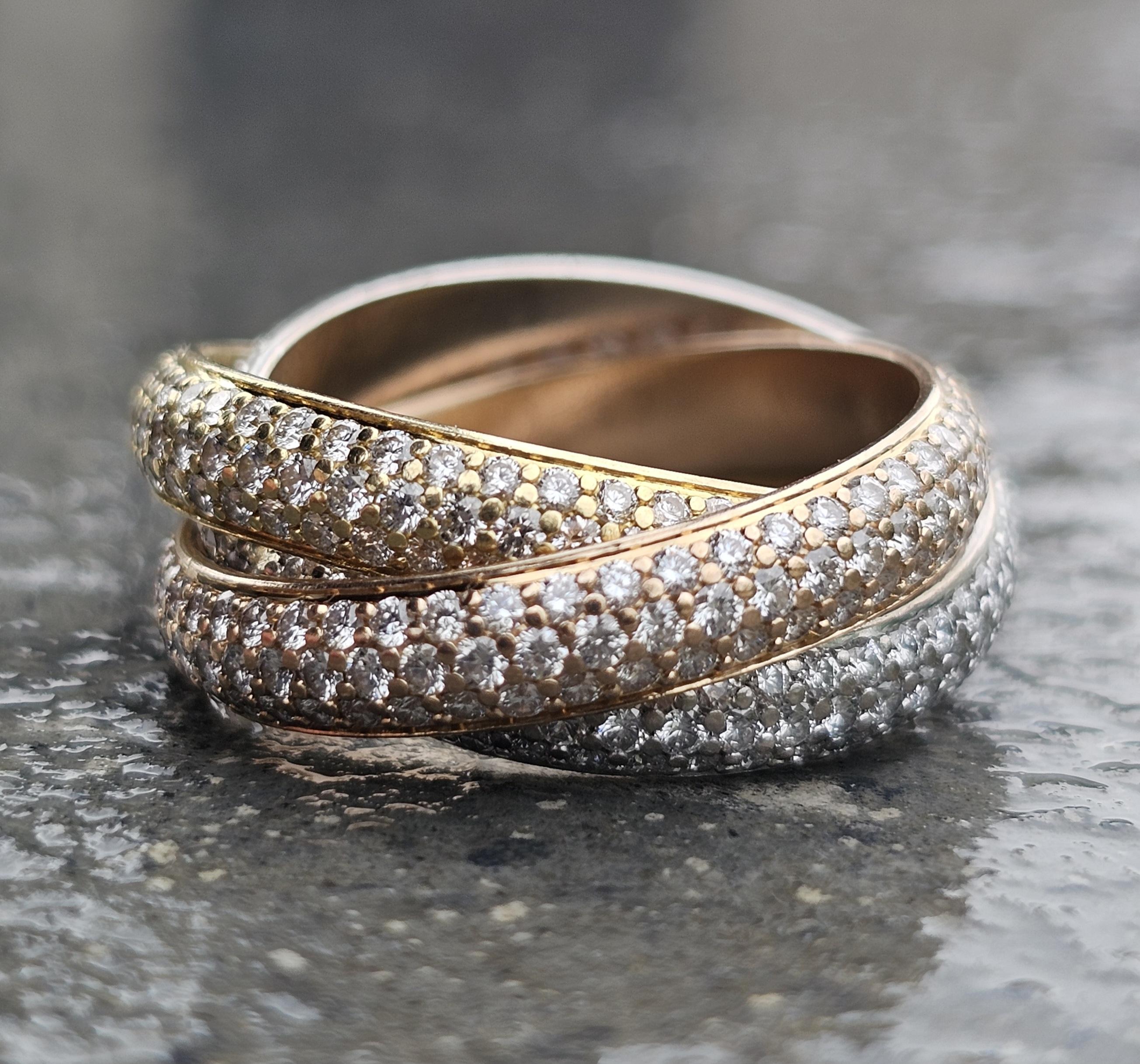 The Cartier Trinity Ring Set showcases an intertwined band design crafted from 18k gold, rose gold, white gold, and yellow gold. Adorned with pave set white diamonds totaling 1.93 carats, this piece exudes elegance. The ring is a size 6 (52) and